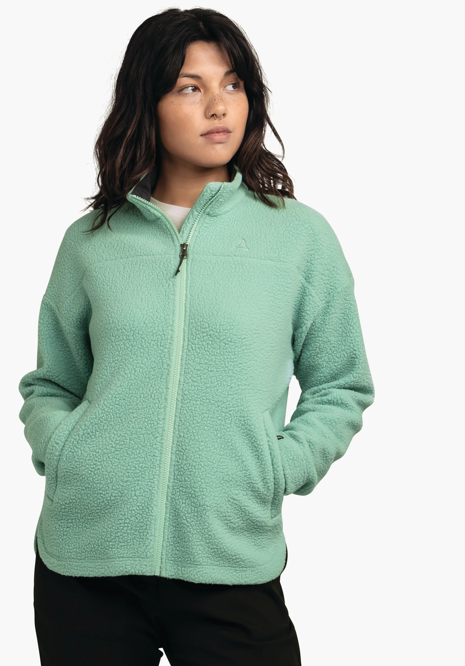 CIRC Fleece Jk Style Purga WMS veste polaire vert clair, portée par un modèle avec les mains dans les poches et regard sur le côté; logo Schöffel sur la poitrine; fond blanc neutre.