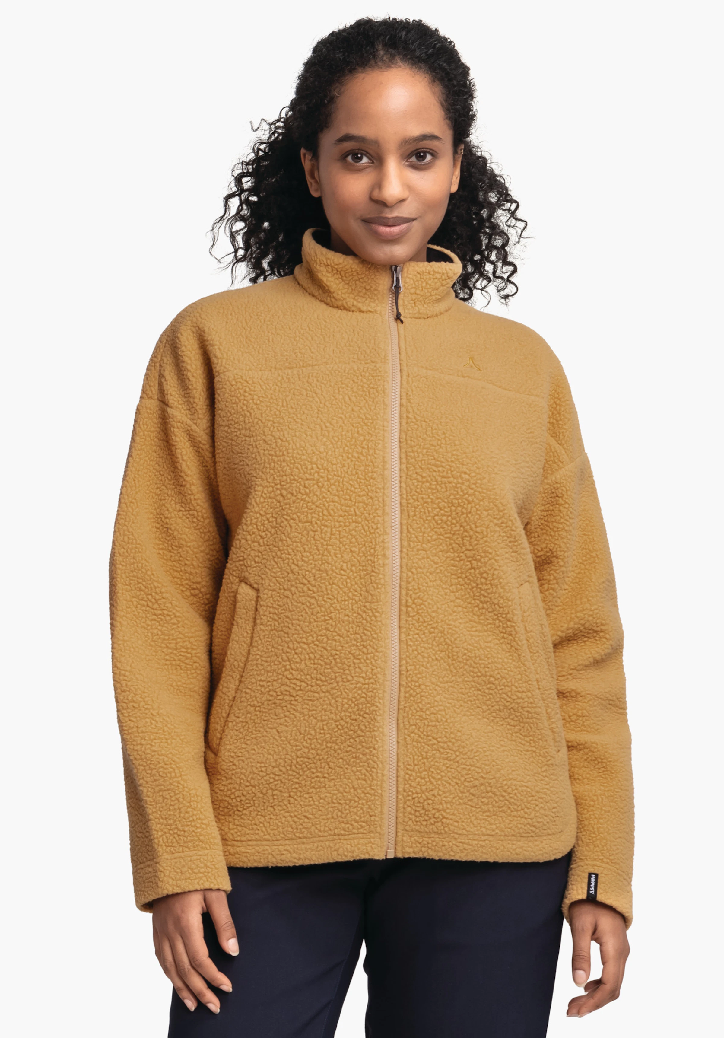 CIRC Fleece Jk Style Purga WMS dunkelgelbe Fleecejacke mit Reißverschluss, Schöffel-Logo auf der Brust, wird von einer Frau stehend getragen; lockere Passform, Hände seitlich, weißer Studiohintergrund.