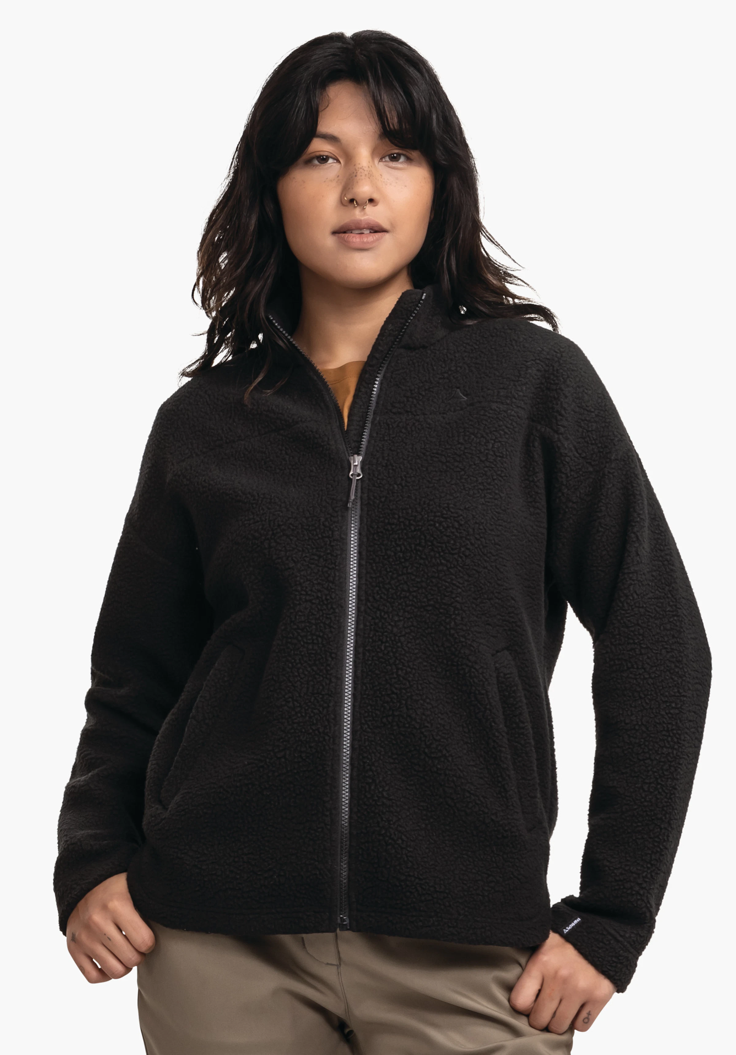 CIRC Fleece Jk Style Purga WMS veste polaire noire avec fermeture éclair fermée, portée par une personne debout avec les mains dans les poches; fond blanc.
