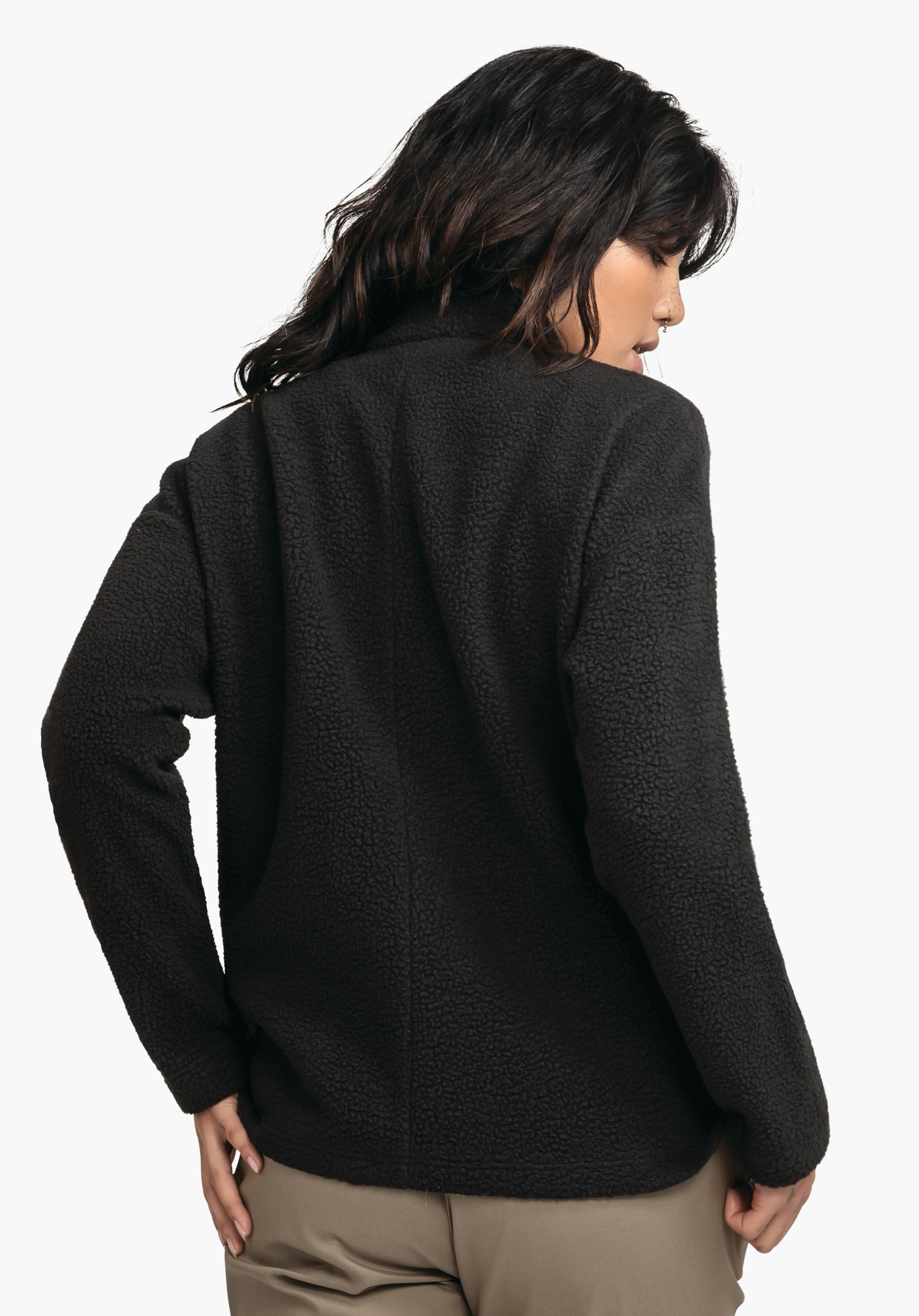 CIRC Fleece Jk Style Purga WMS black fleece jacket worn from the back by a woman looking over her shoulder; loose fit with textured surface; light neutral studio background.