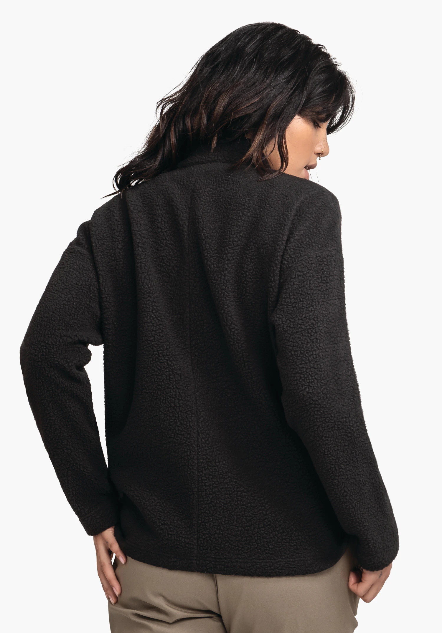 CIRC Fleece Jk Style Purga WMS zwarte fleecejas, van achteren gedragen door een vrouw die over de schouder kijkt; losvallend met gestructureerd oppervlak, lichte neutrale studioachtergrond.