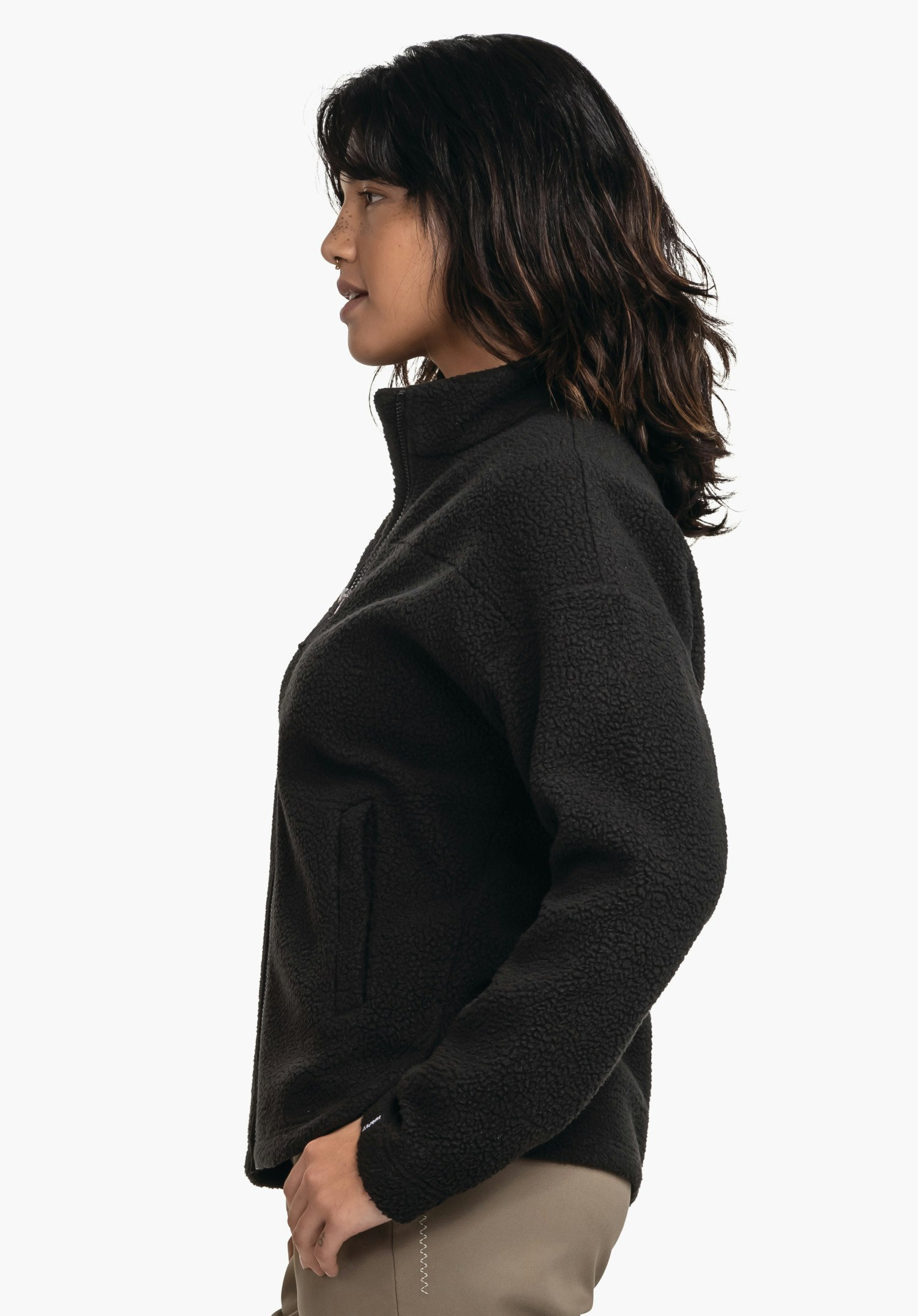 CIRC Fleece Jk Style Purga WMS black fleece jacket worn by a side-on standing person looking left with one hand in the pocket; dark brown hair; white background.