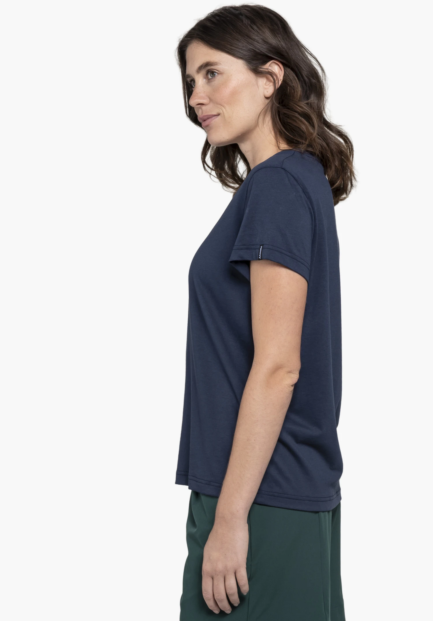 T Shirt Style Collada WMS wird von einem Model getragen, das seitlich steht. Das blaue Shirt zeigt ein kleines Schöffel-Logo am Ärmel und wird vor einem neutralen Hintergrund präsentiert.