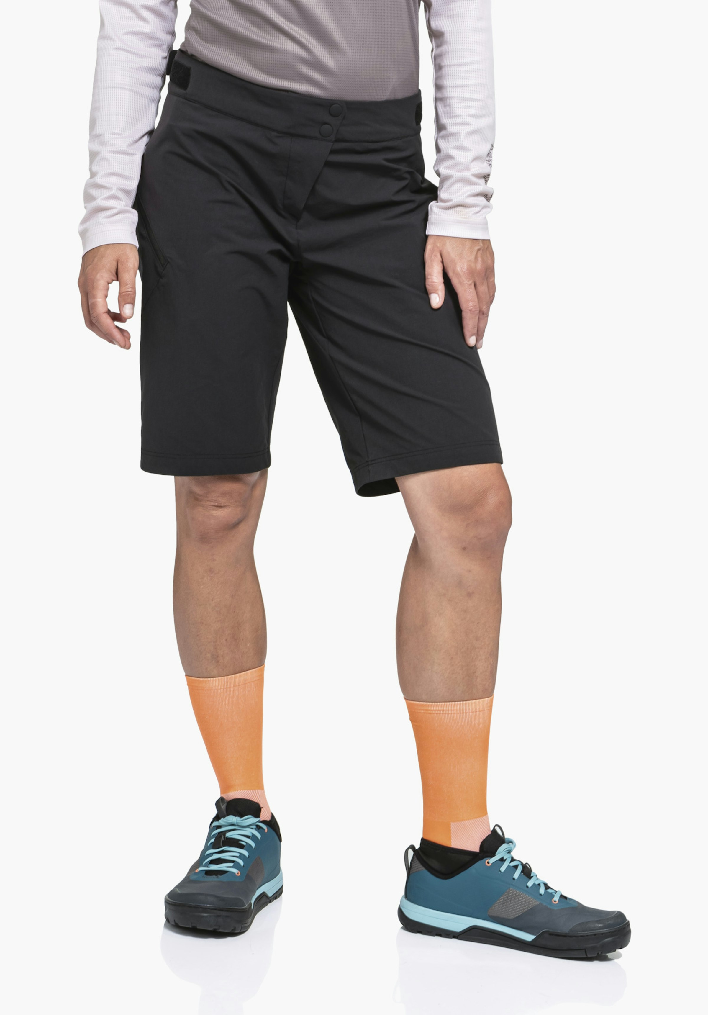 Shorts Style Puula WMS short noir; personne debout bras le long du corps, portant des chaussettes orange et des chaussures bleu foncé devant un fond studio blanc.