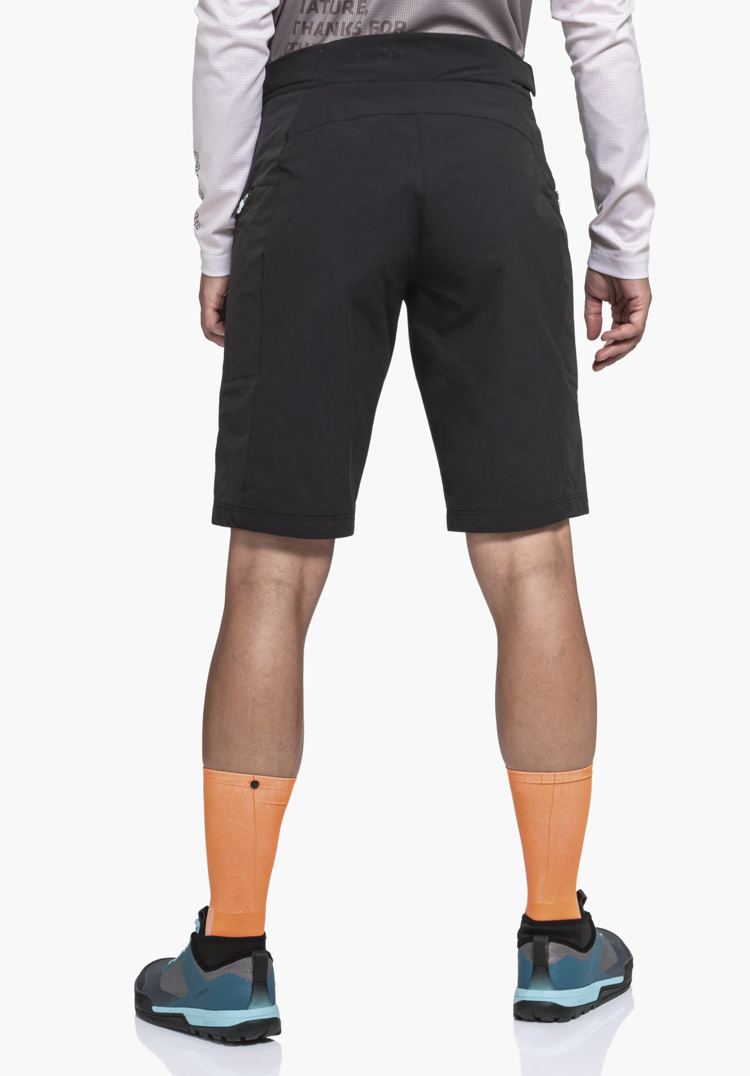 Shorts Style Puula WMS black shorts worn by a standing person with back to the camera; light pink long-sleeve top (text: “ATURE THANKS FOR”), orange long socks, light blue and black trekking shoes; white background.