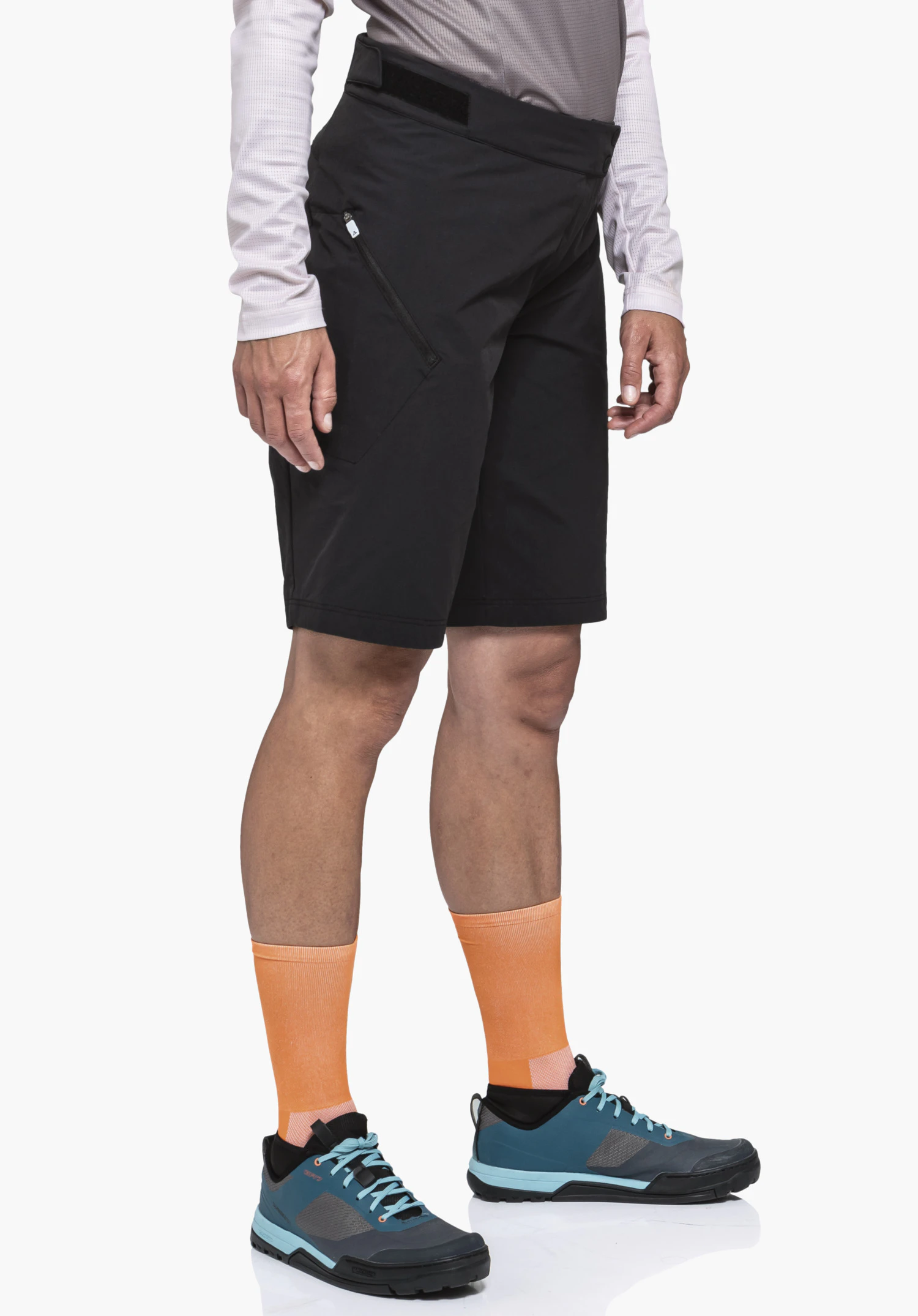 Shorts Style Puula WMS black shorts worn by a standing person; side zip pocket visible; light orange socks and blue trekking shoes; white background.