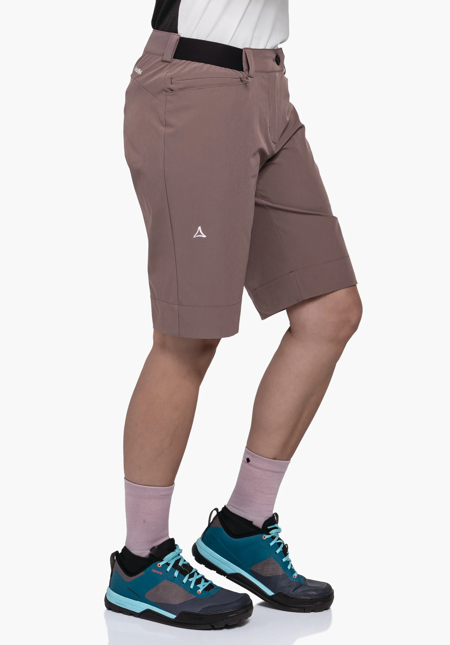 Shorts Style Keitele WMS in bruin, gepresenteerd in een zijaanzicht op een model tegen een neutrale achtergrond. Het model staat in profiel, waarbij het subtiele Schöffel-logo op het been goed zichtbaar is.