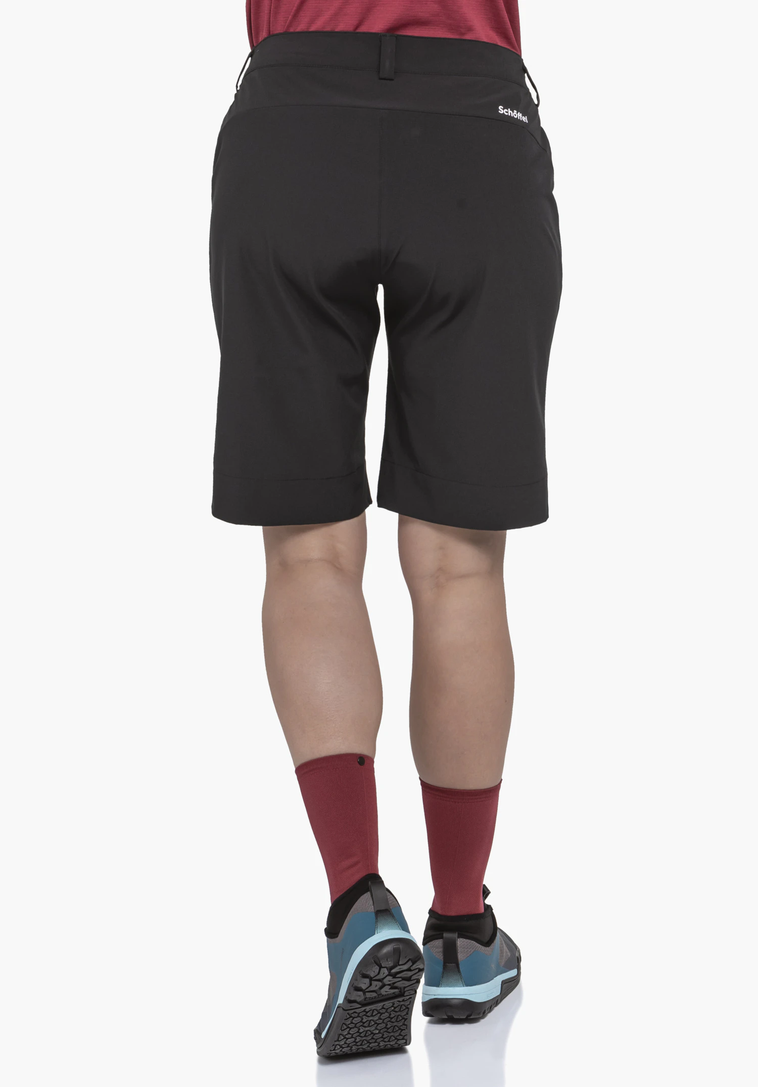 Shorts Style Keitele WMS zwarte shorts, van achteren gedragen; persoon staat op een witte achtergrond en draagt donkerrode sokken en lichtblauwe en zwarte schoenen, opschrift Schöffel op de rechterheup.