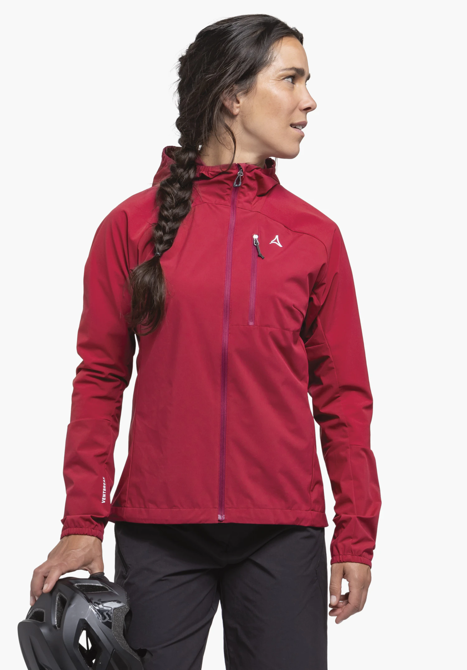 Hybrid Jk Style Mamry WMS on a model. The woman stands facing the front, looks to the side and wears the jacket in red. She is holding a cycling helmet in her hand, the Schöffel logo is visible on the chest, photographed against a neutral background.