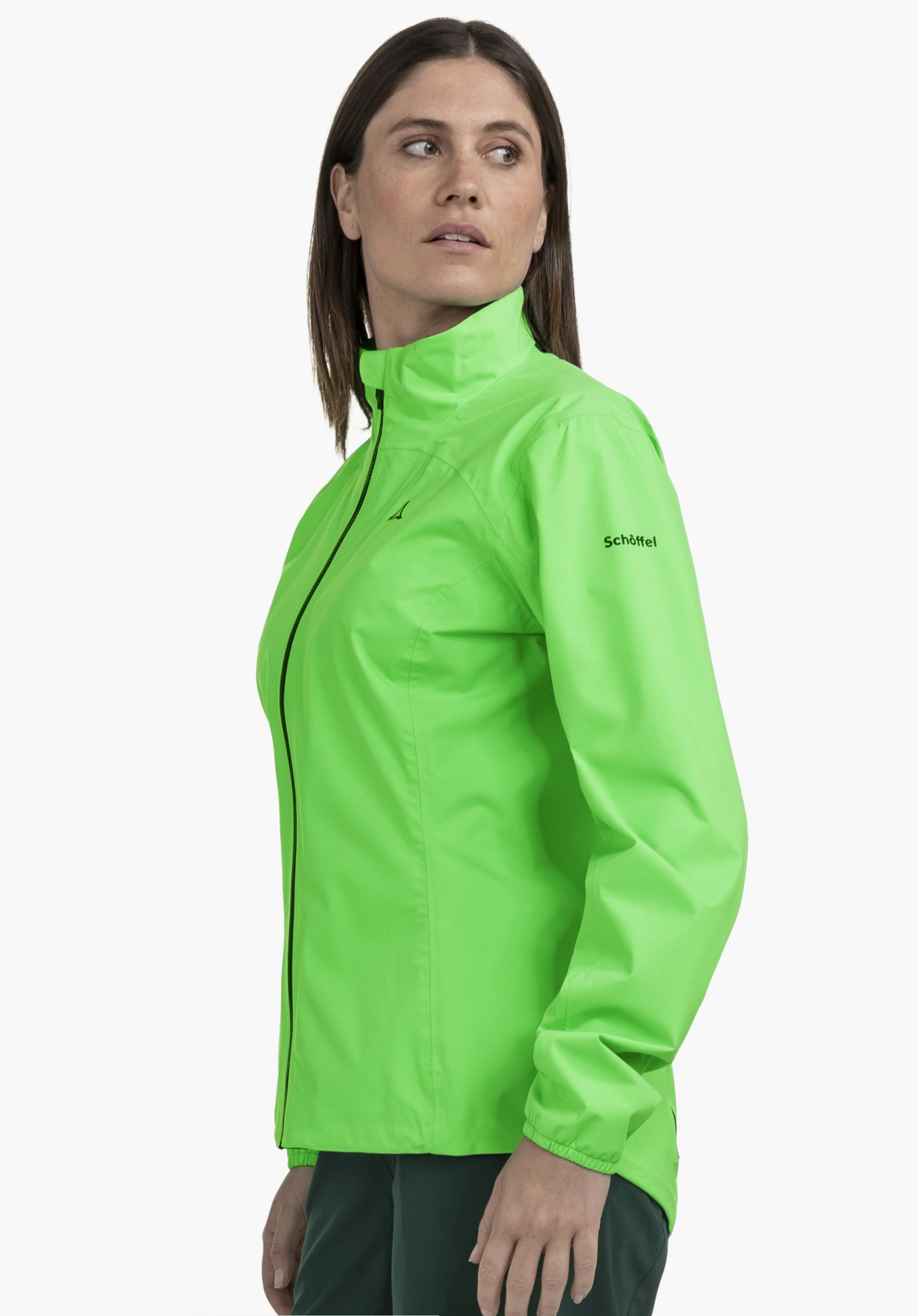 Jacket Style Lurbek WMS: Eine Frau in der leuchtend grünen Jacke steht seitlich vor einem neutralen Hintergrund und blickt über ihre Schulter, während das dezente Schöffel-Logo auf dem Oberarm für einen Akzent sorgt.