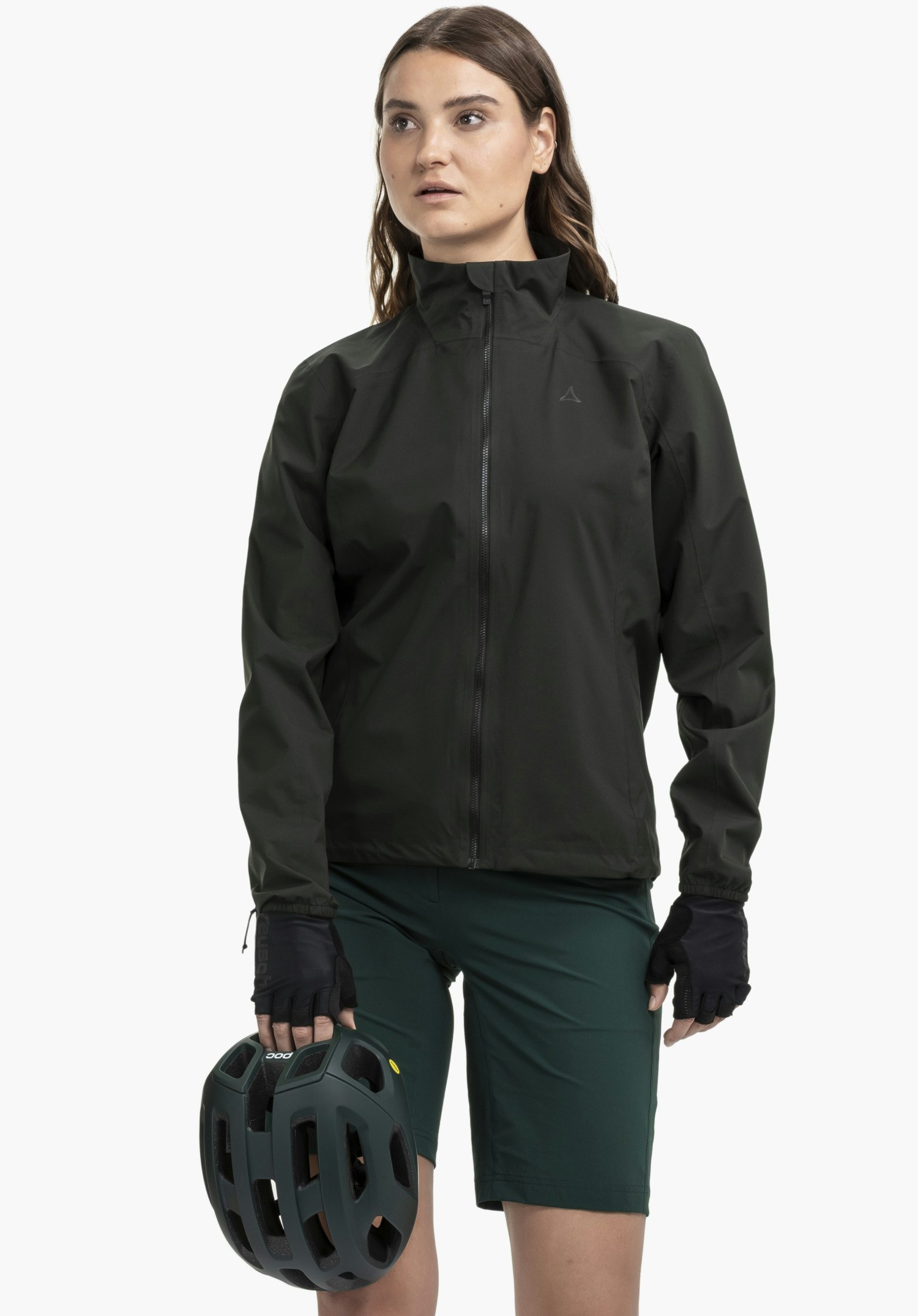 Jacket Style Lurbek WMS on a model standing frontally and holding a cycling helmet. The jacket is shown in black with the Schöffel logo on the left chest against a neutral background.