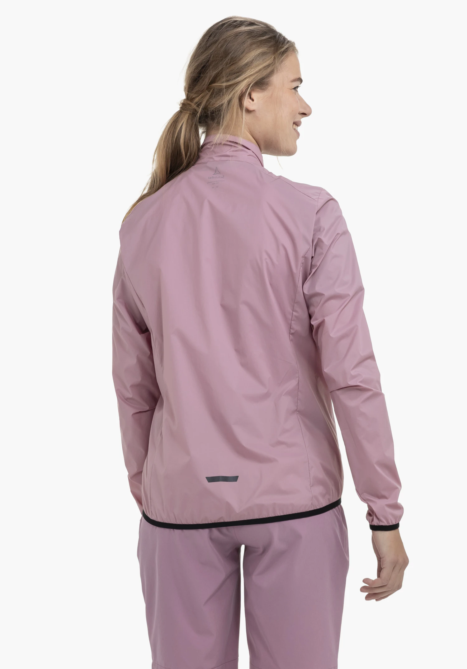 Jacket Style Cannobio WMS in Rosa zeigt sich in der Rückenansicht an einem Model vor einem neutralen Hintergrund mit sichtbarem Schöffel-Logo im Nackenbereich.