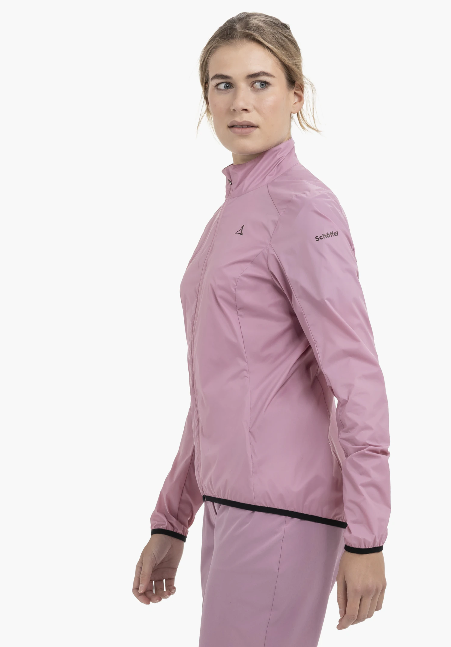 Jacket Style Cannobio WMS in zartem Rosa präsentiert sich hier in einer seitlichen Trageansicht vor einem neutralen Hintergrund. Die Passform der Jacke ist deutlich zu erkennen, während das dezente Schöffel-Logo auf dem Oberarm für den charakteristischen Markenlook sorgt.