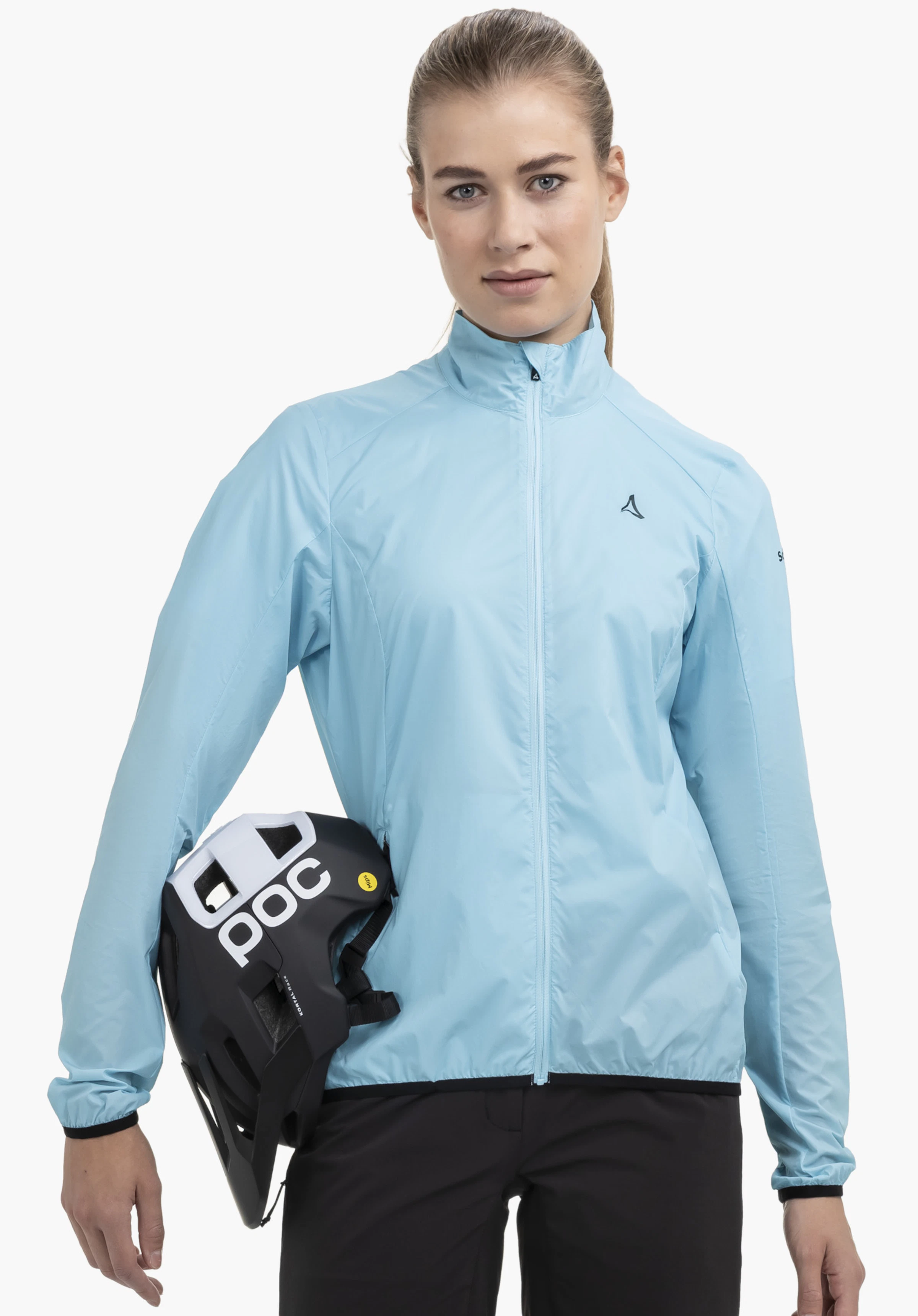 Jacket Style Cannobio WMS wird von einem Model in der Frontalansicht getragen, das einen Fahrradhelm unter dem rechten Arm hält. Die blaue Jacke zeigt das Schöffel-Logo auf der linken Brust und wird vor einem neutralen Hintergrund präsentiert.