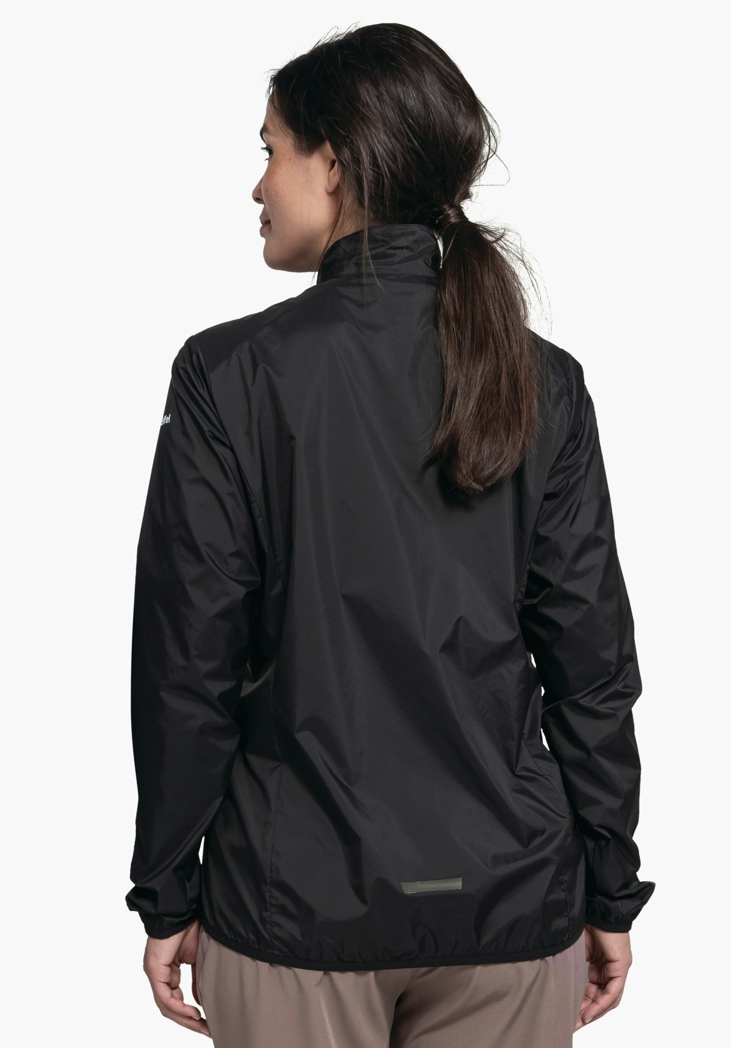 Jacket Style Cannobio WMS worn by a model in a back view. The black jacket reveals part of the Schöffel logo on the left sleeve. The model stands in front of a neutral background and looks slightly to the left.