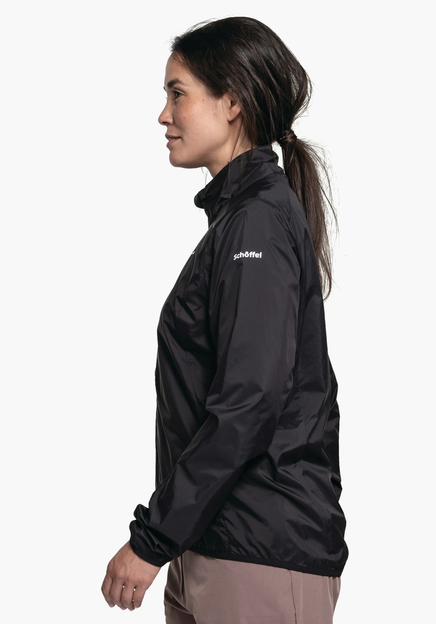 Jacket Style Cannobio WMS in timeless black. The model stands sideways against a neutral background, showcasing the jacket's silhouette with the white Schöffel logo on the upper arm subtly visible.