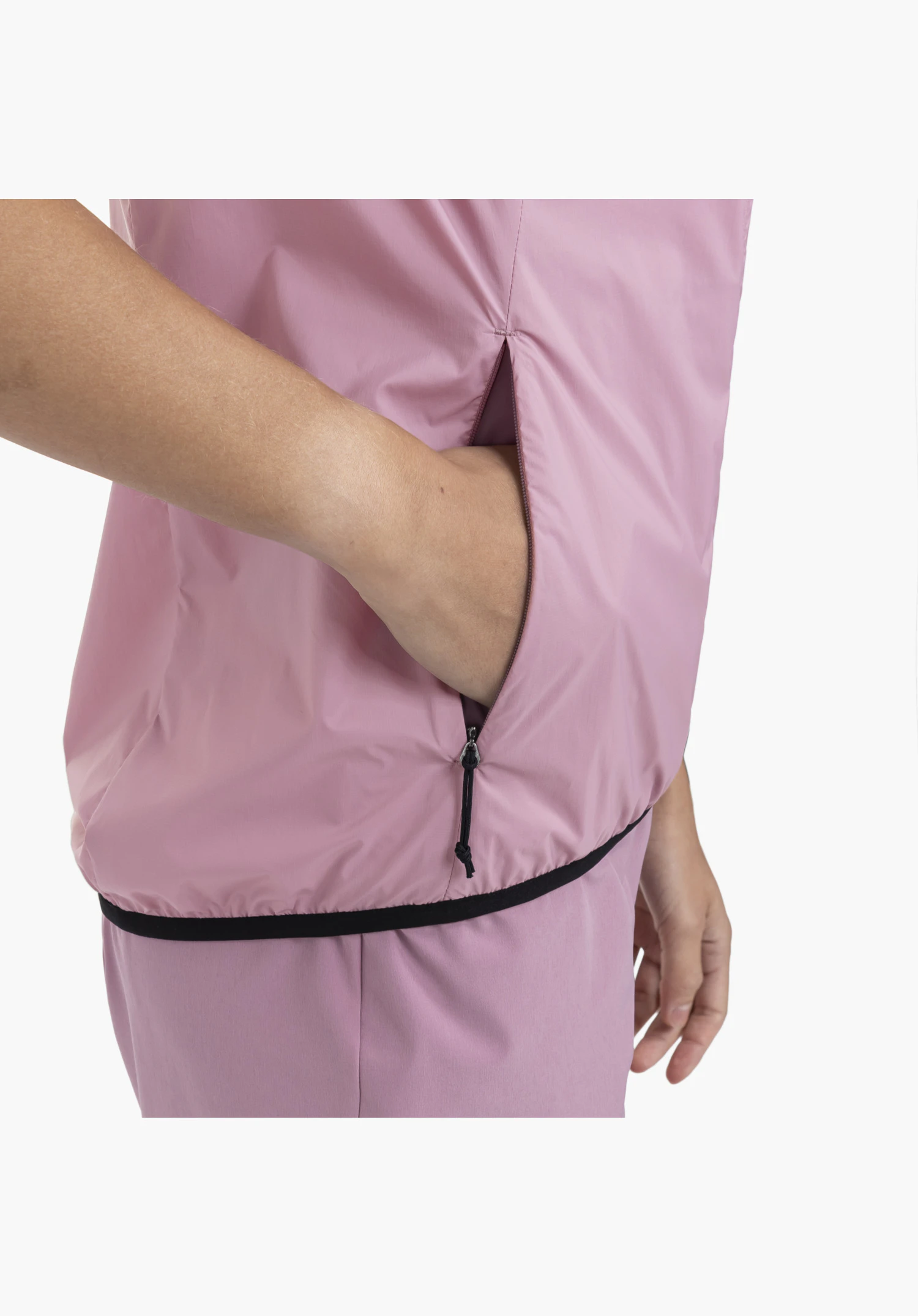 Vest Style Cannobio WMS, focusing on the side zip pocket in the pink fabric with a hand reaching inside and the contrasting black hem binding, close-up shot against a white/neutral background.