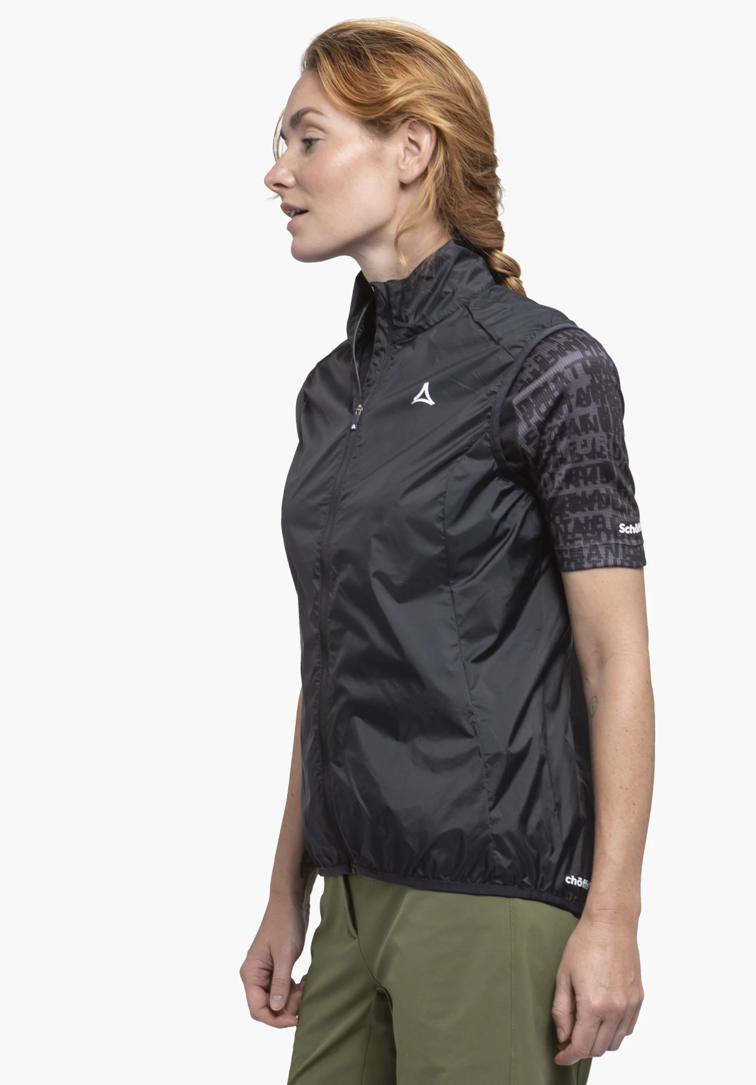Vest Style Cannobio WMS in timeless black. A female athlete is standing in profile against a neutral background, showcasing the lightweight vest with the premium Schöffel logo on the chest and hem.