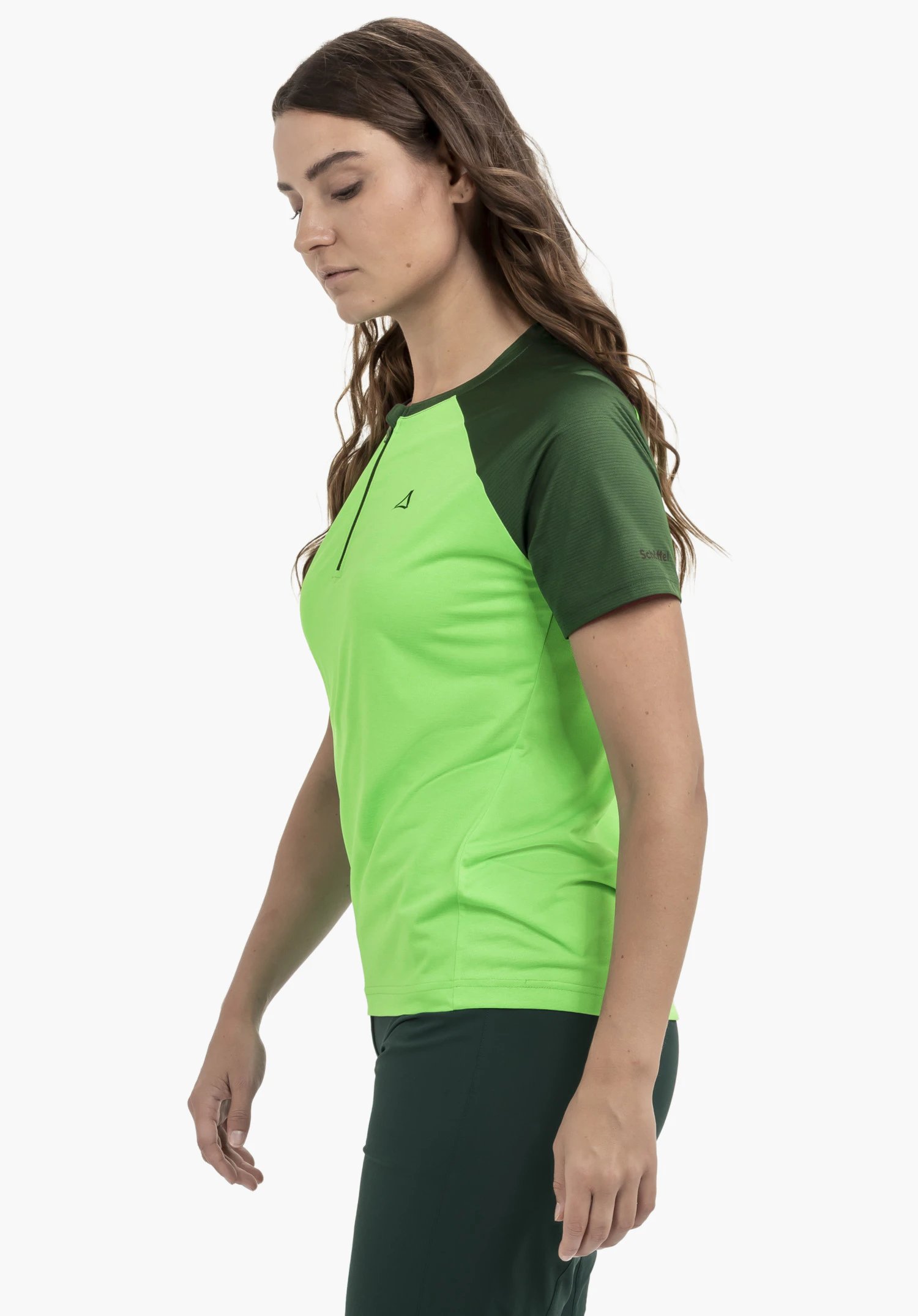 CIRC Shirt Style Wetluga WMS: Das Model steht leicht seitlich vor einem neutralen Hintergrund. Das Shirt in verschiedenen Nuancen von Grün ist mit dem dezenten Schöffel-Logo auf dem Ärmel versehen.