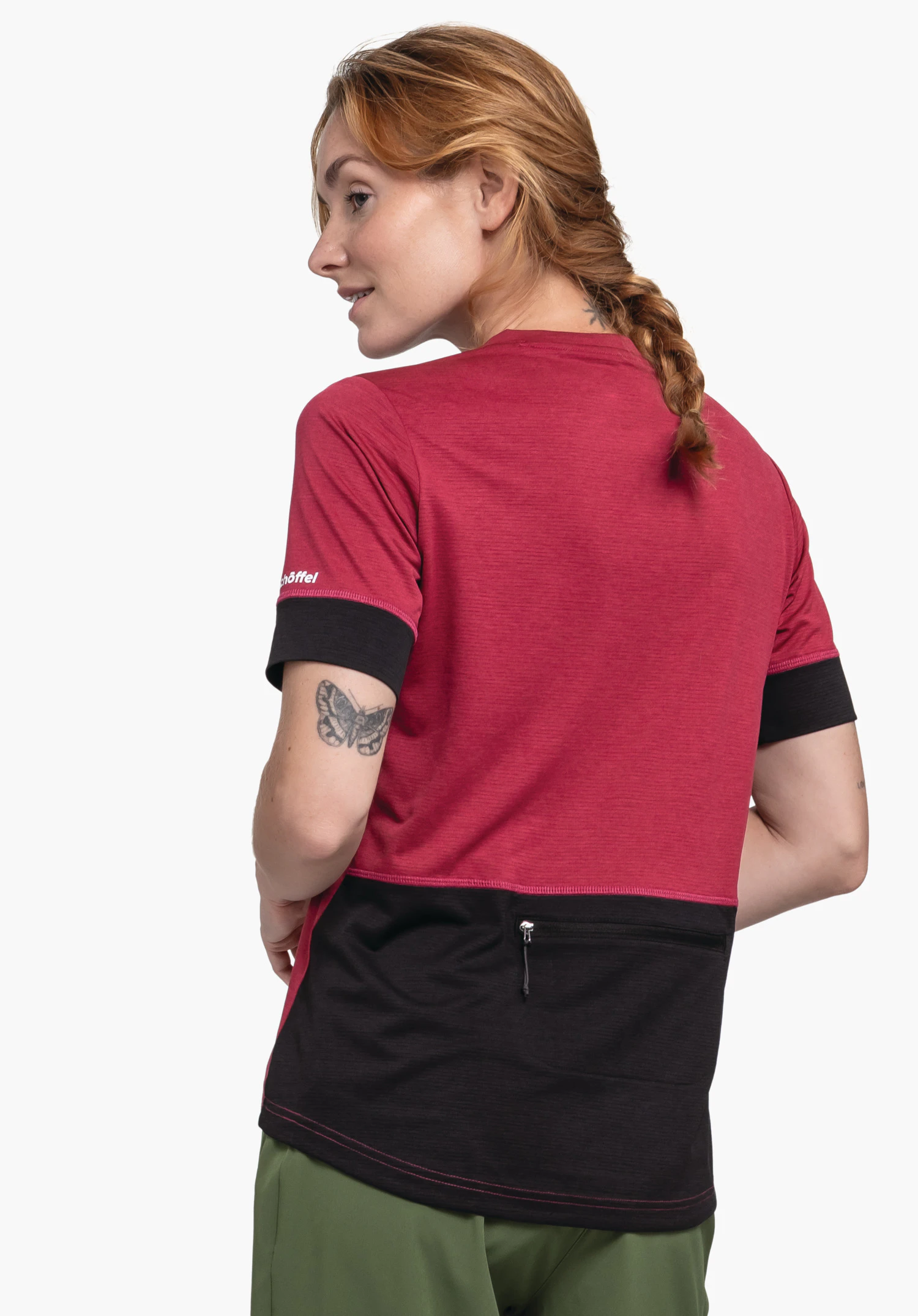 CIRC Shirt Style Pinega WMS t-shirt rouge foncé avec empiècement noir au bas du dos et poche zippée; personne se tournant à moitié sur le côté, tresse visible, tatouage papillon sur le haut du bras. Texte sur la manche: "Schöffel".