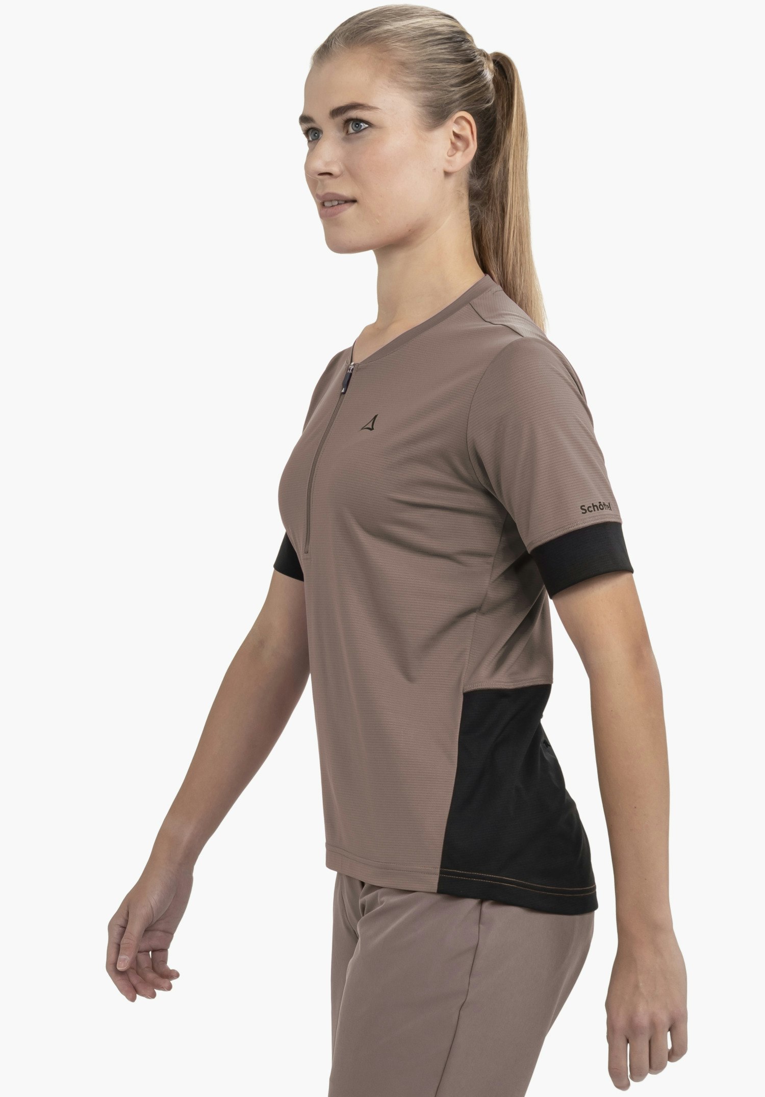CIRC Shirt Style Pinega WMS : Une athlète pose de profil devant un fond neutre, vêtue du t-shirt dans un coloris marron. Le logo Schöffel est discrètement mais clairement visible sur la poitrine et la manche.