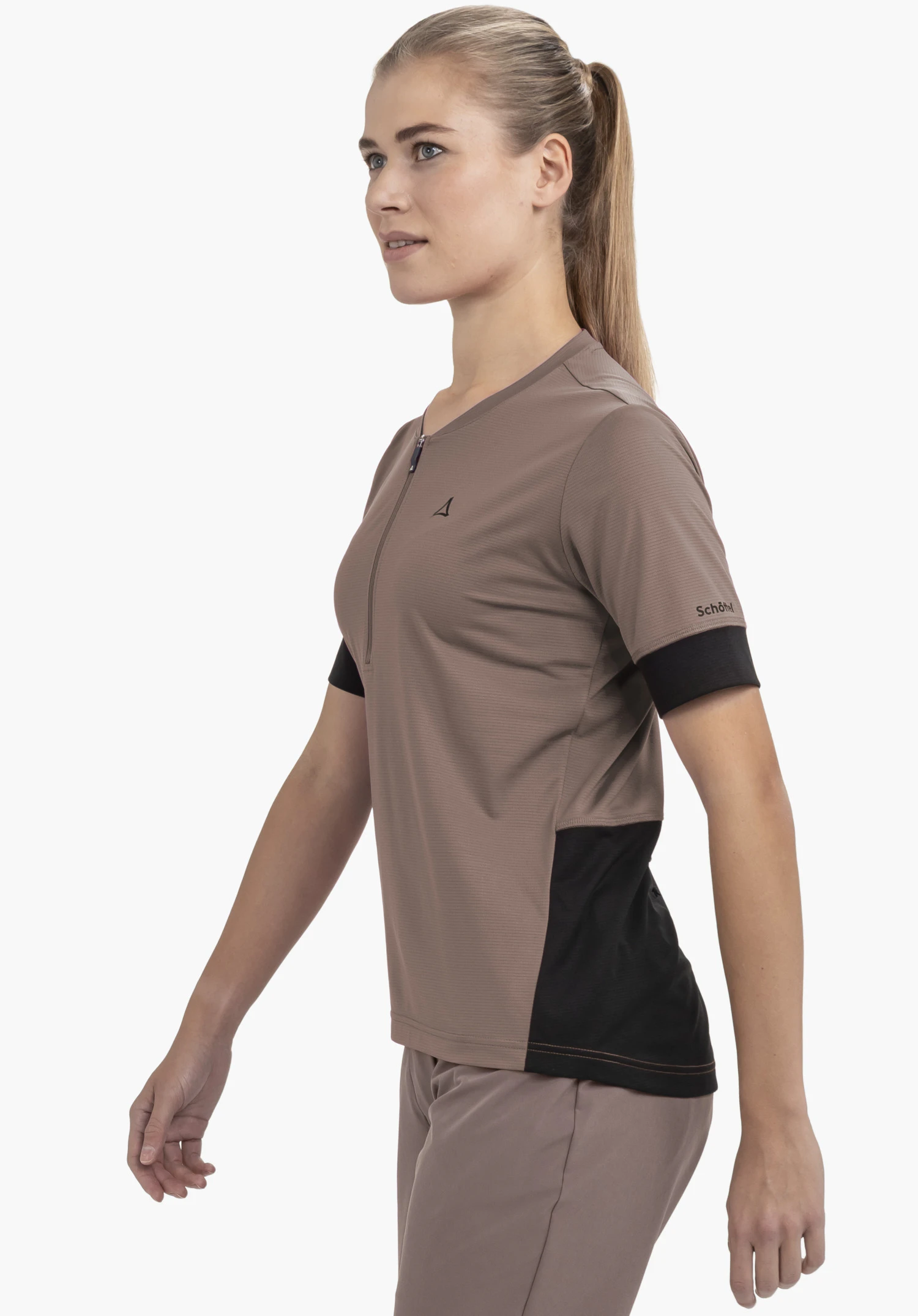 CIRC Shirt Style Pinega WMS : Une athlète pose de profil devant un fond neutre, vêtue du t-shirt dans un coloris marron. Le logo Schöffel est discrètement mais clairement visible sur la poitrine et la manche.
