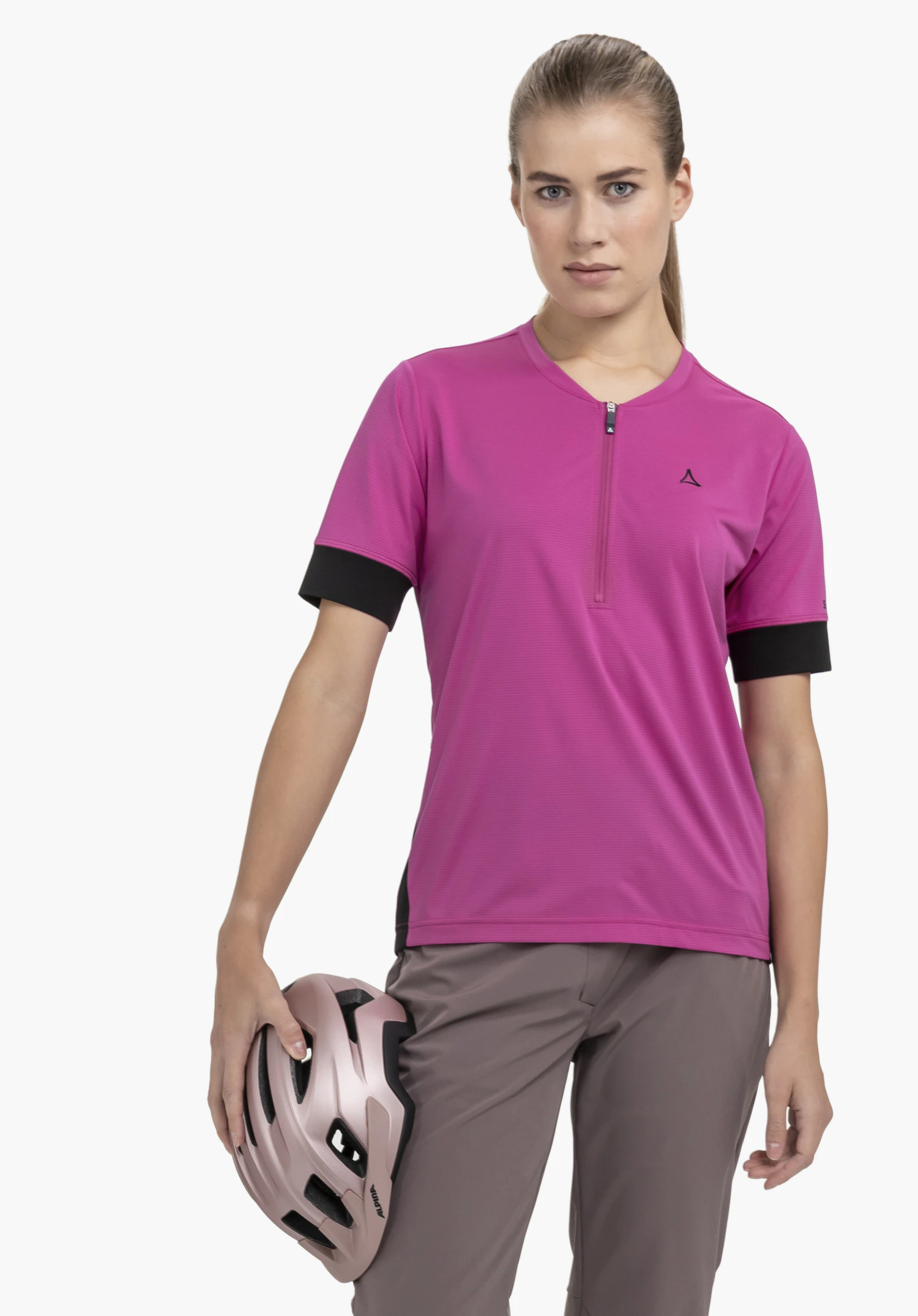 CIRC Shirt Style Pinega WMS: Eine Sportlerin steht frontal vor einem neutralen Hintergrund und trägt das Shirt in leuchtendem Pink. Das Design wird durch schwarze Akzente an den Ärmeln und ein dezentes Schöffel-Logo auf der Brust ergänzt, während sie einen Fahrradhelm in der Hand hält.