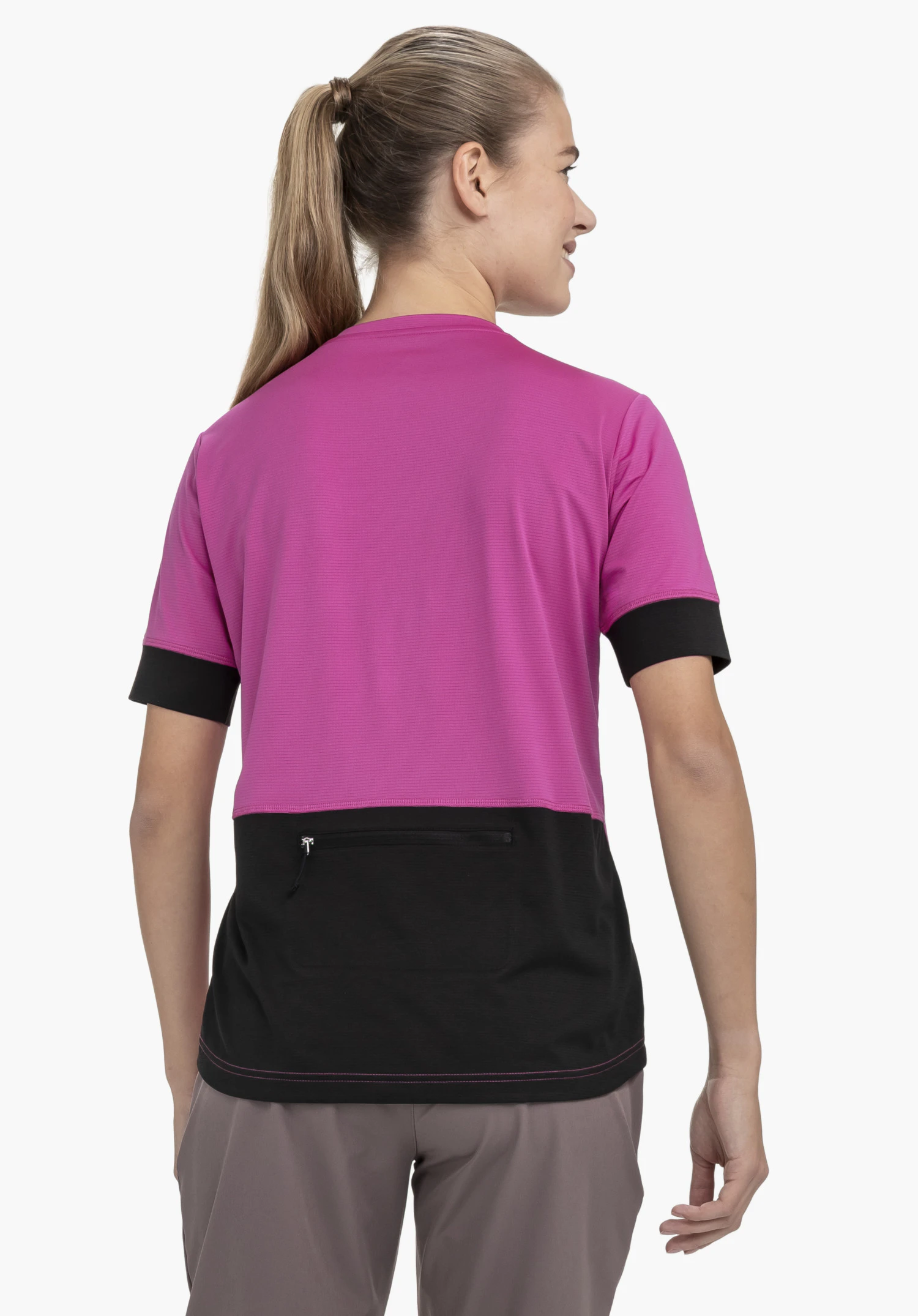CIRC Shirt Style Pinega WMS in leuchtendem Pink präsentiert sich in der Rückenansicht vor einem neutralen Hintergrund. Das Model steht leicht seitlich und zeigt das durchdachte Design mit kontrastierender schwarzer Tasche am unteren Rücken.