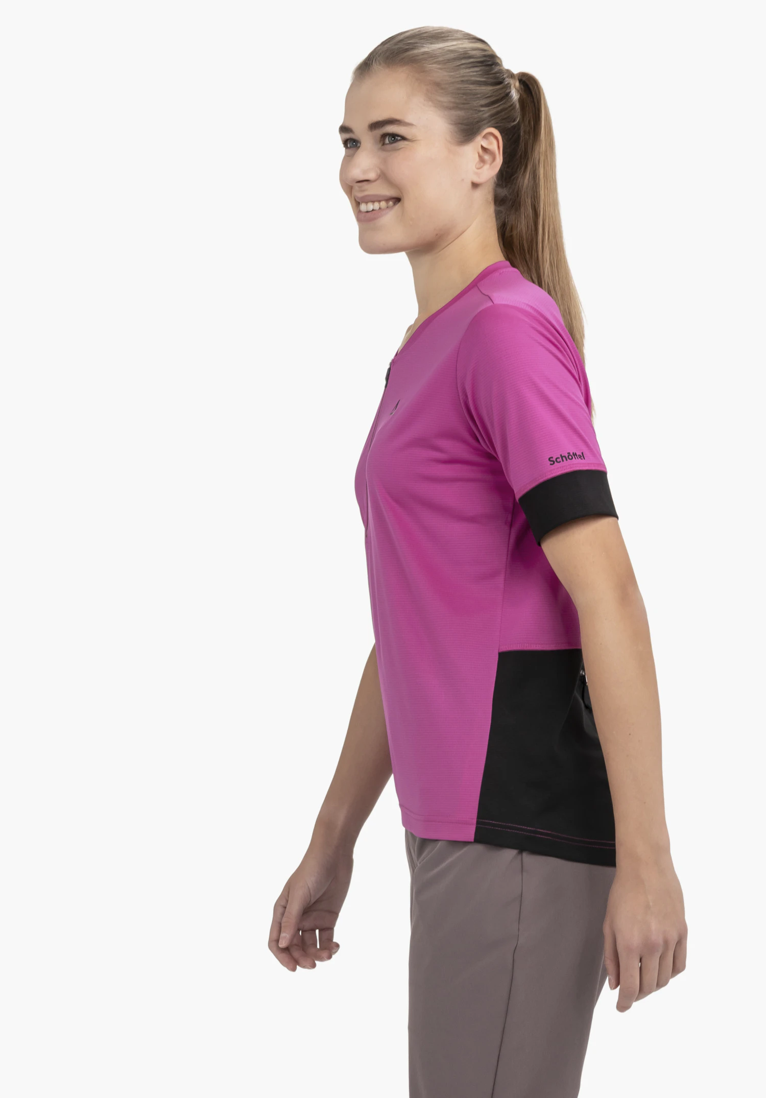 CIRC Shirt Style Pinega WMS in leuchtendem Pink. Das Model steht seitlich vor einem neutralen Hintergrund und präsentiert das Shirt. Das schwarze Schöffel-Logo am Ärmel setzt einen markanten Kontrast zum pinkfarbenen Stoff.