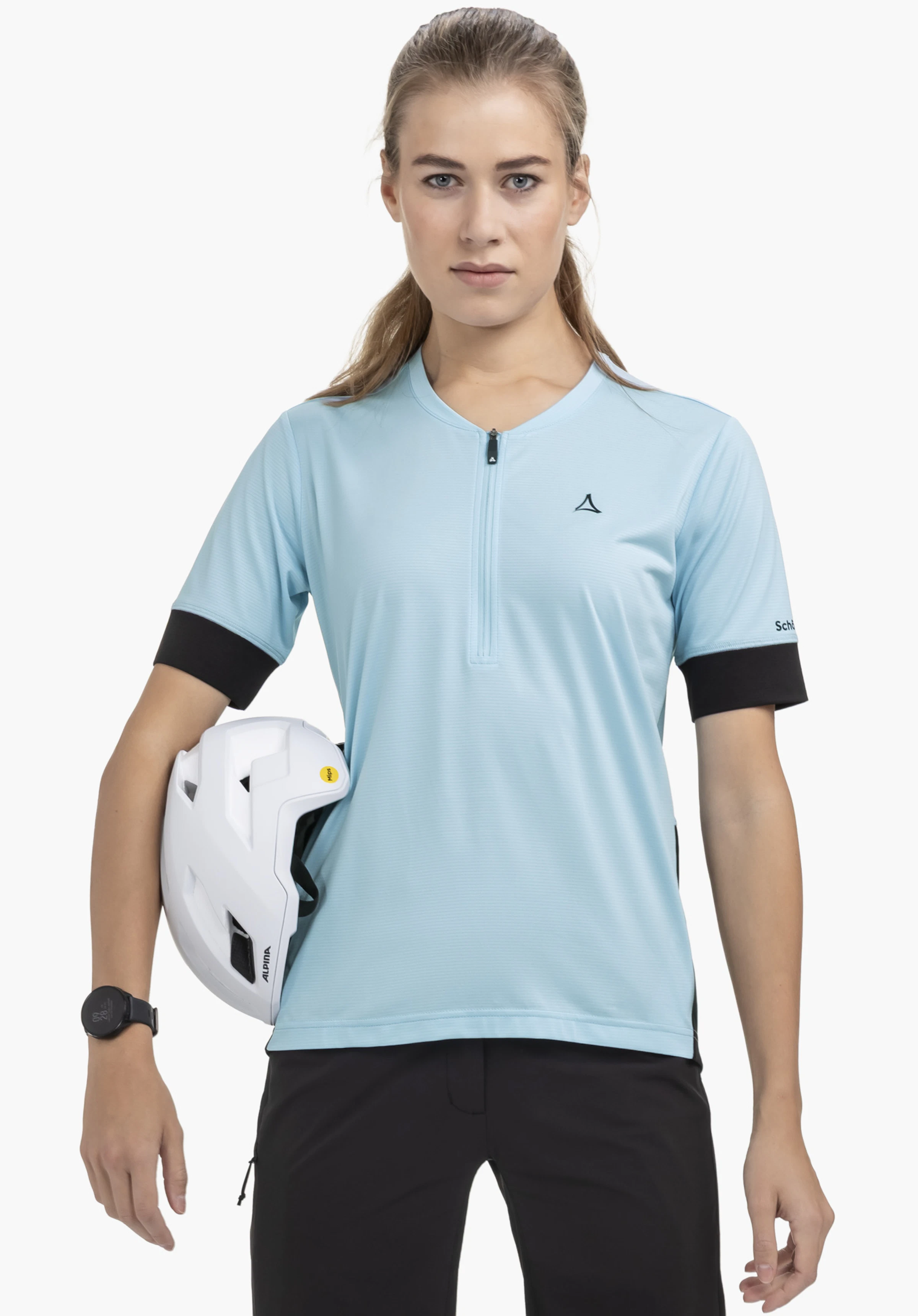 CIRC Shirt Style Pinega WMS : Le mannequin pose de face sur un fond neutre, portant le t-shirt en bleu. Le logo Schöffel discret est visible sur la poitrine et la manche, tandis que le mannequin tient un casque de vélo sous le bras, soulignant ainsi sa vocation sportive.