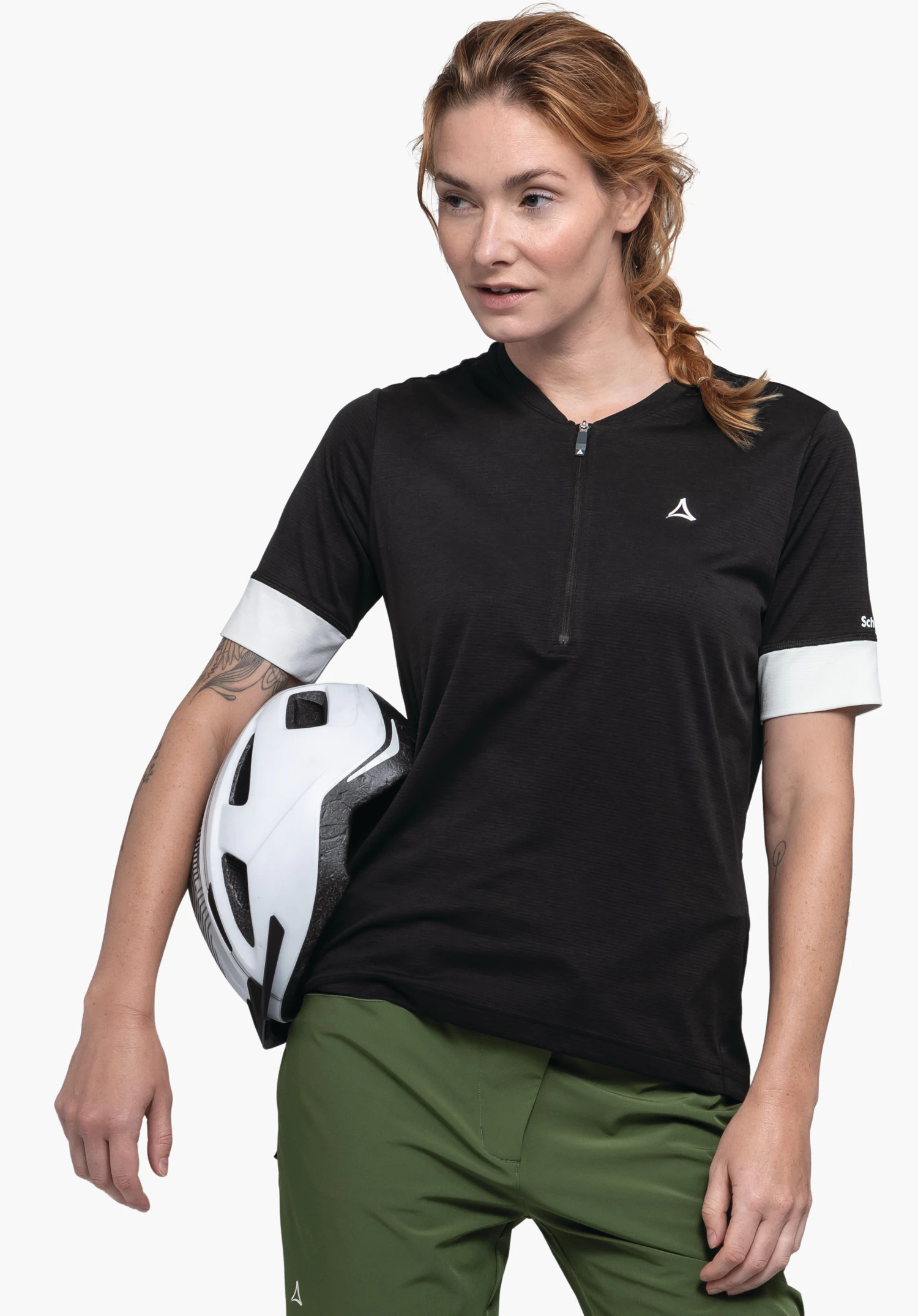 CIRC Shirt Style Pinega WMS in der Farbe Schwarz vor einem neutralen Hintergrund. Die Sportlerin steht leicht seitlich gewandt und hält einen Fahrradhelm unter dem Arm. Das weiße Schöffel-Logo ist dezent auf der Brust platziert.