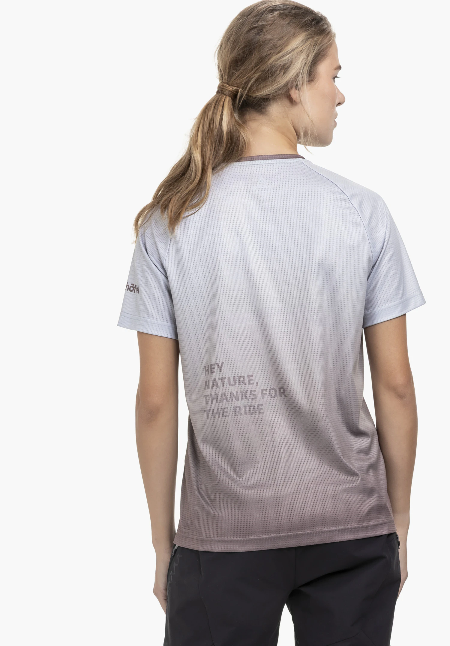 Shirt Style Koitere WMN in der Rückenansicht: Das Modell steht vor einem neutralen Hintergrund und trägt das Shirt mit seinem modischen Farbverlauf in Braun. Ein dezentes Schöffel-Logo ist am Ärmel zu sehen, während der markante Rückenprint das Outdoor-Statement unterstreicht.