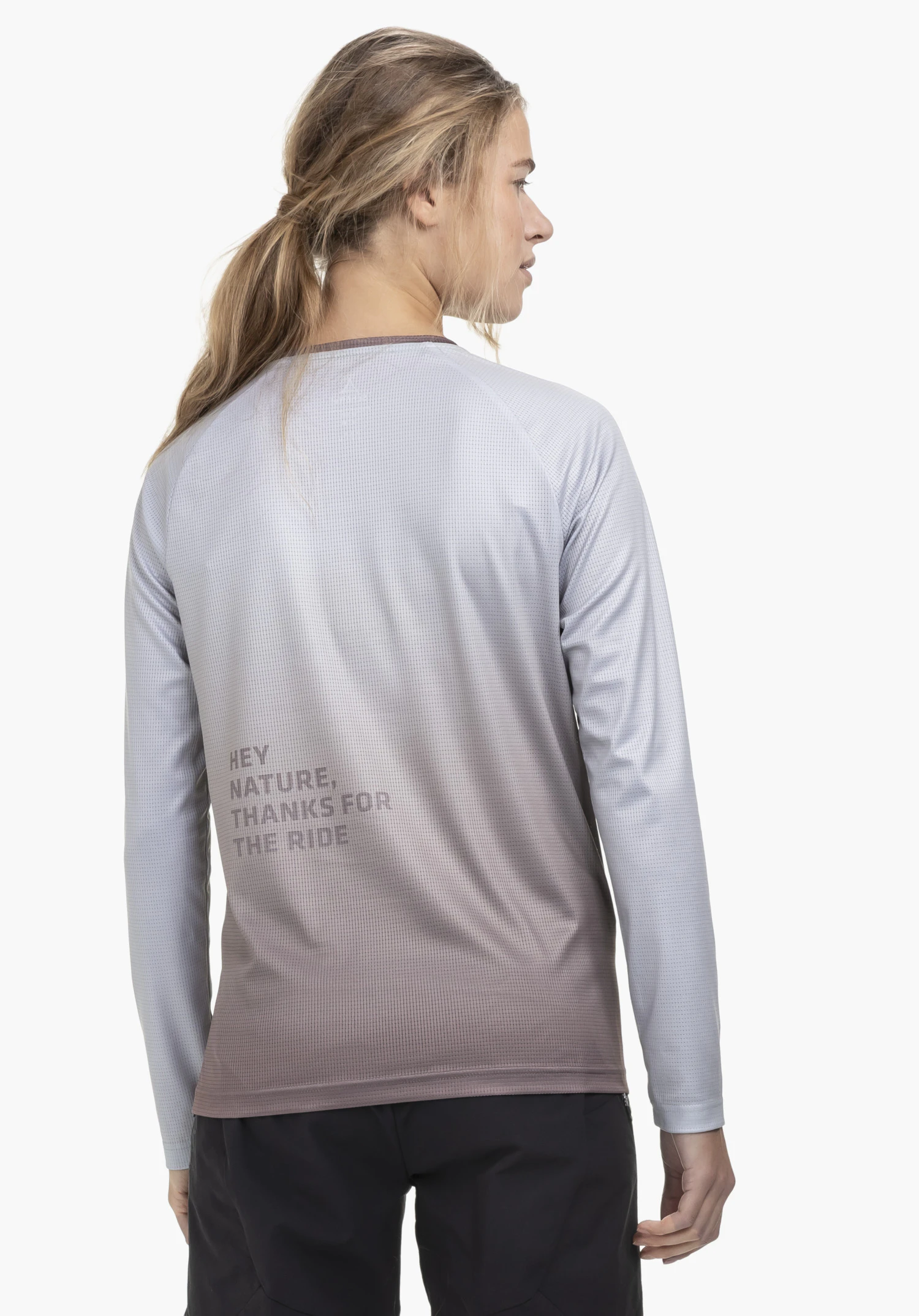 Longsleeve Style Koitere WMN en lila sur un fond neutre : Le mannequin est photographié de dos, mettant en valeur l'imprimé discret et le dégradé de couleurs, tout en jetant un regard par-dessus l'épaule.