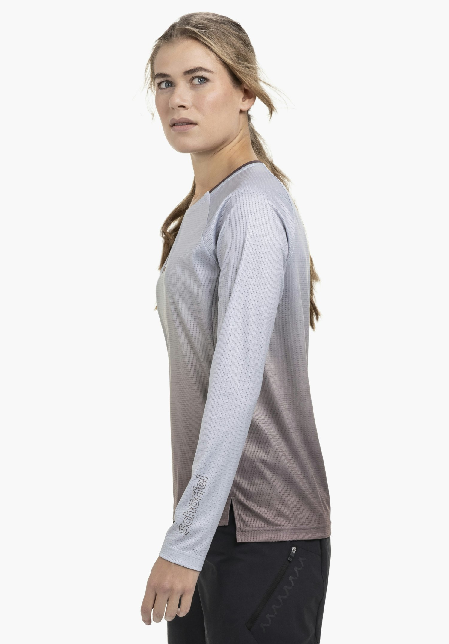 Longsleeve Style Koitere WMN in lila, gedragen door een model in zijwaartse pose tegen een neutrale achtergrond. De hoogwaardige stof is goed zichtbaar, waarbij het subtiele Schöffel-logo op de mouw zorgt voor een sportieve uitstraling.