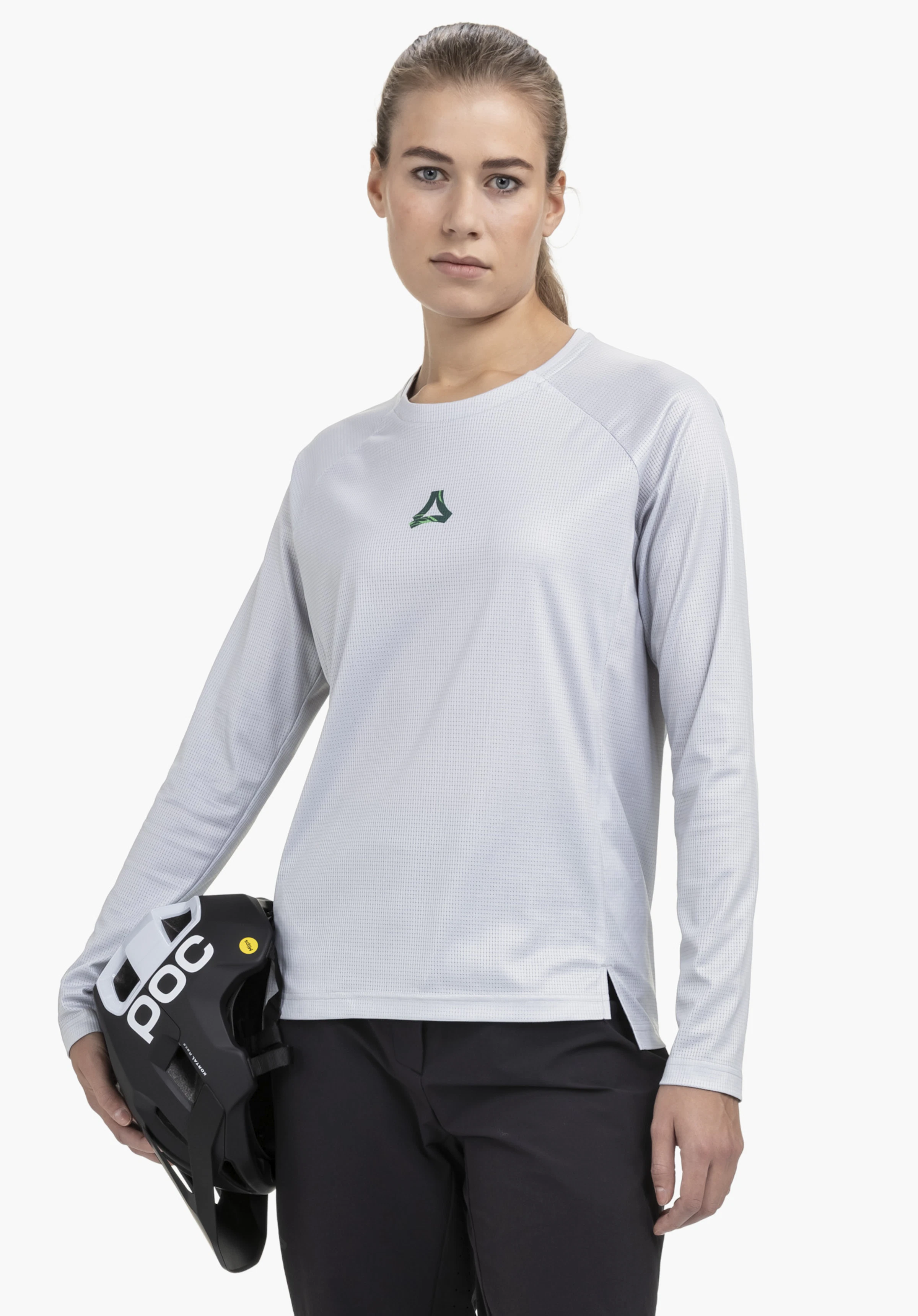 Longsleeve Style Koitere WMN in Grau, präsentiert von einem Model auf einem neutralen Hintergrund. Das Model blickt frontal in die Kamera und hält einen Helm in der Hand. Das dezente Schöffel-Logo ist im Brustbereich gut sichtbar.