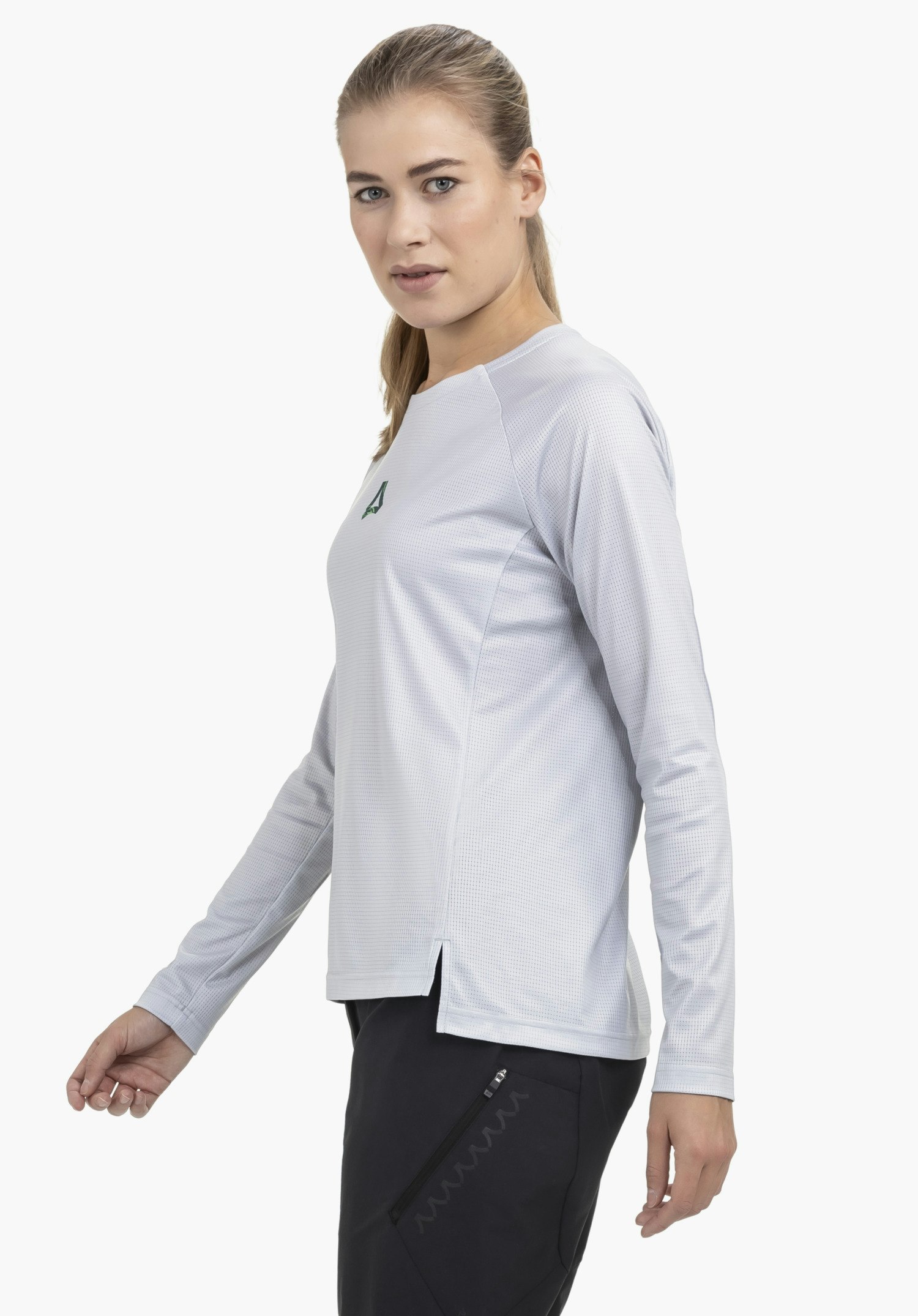 Longsleeve Style Koitere WMN in grey, shown on a model standing in a side-profile pose. The longsleeve features a textured finish and a subtle Schöffel logo on the chest. The photo is set against a neutral background.