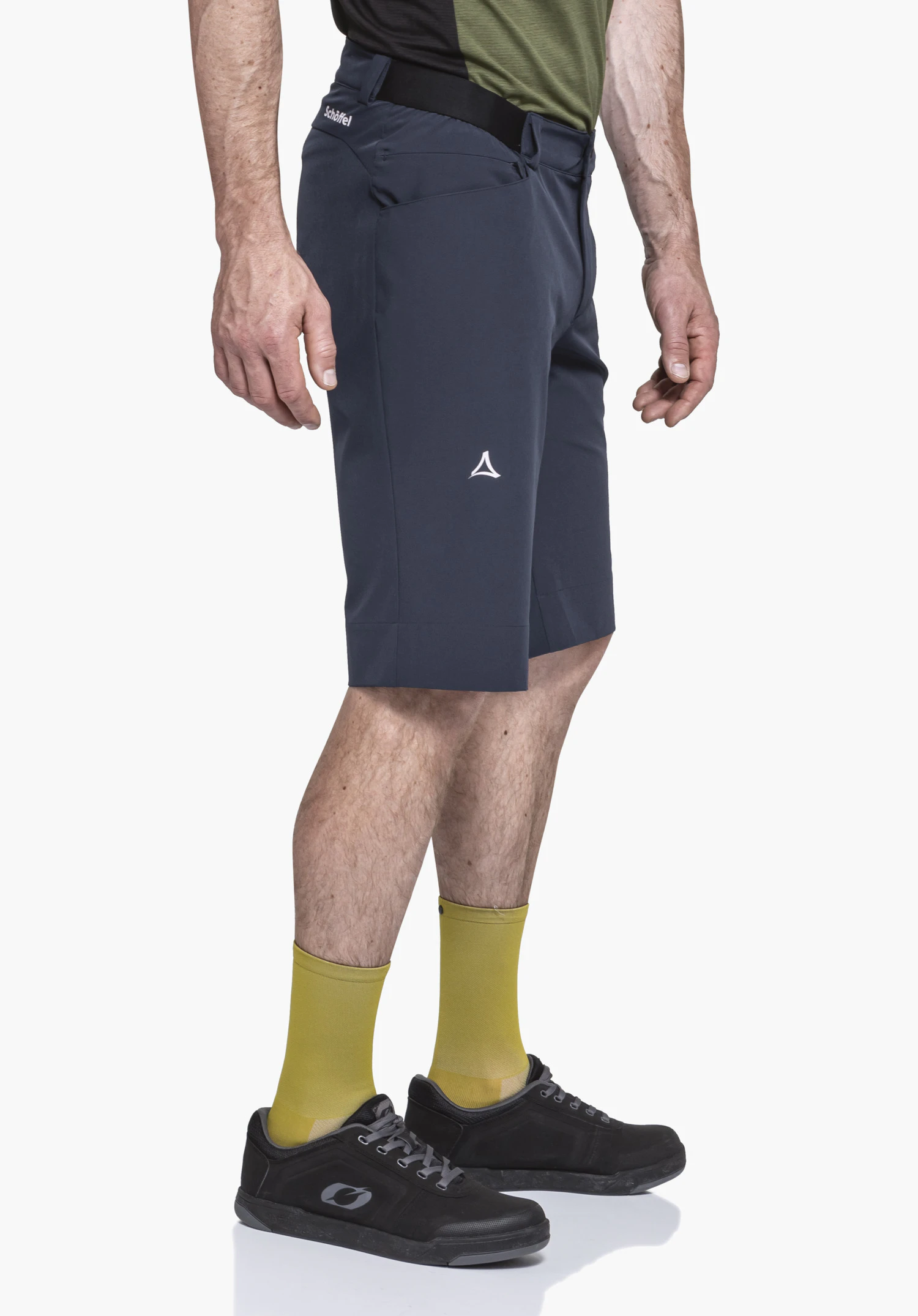 Shorts Style Keitele MNS in blue: A model is standing sideways against a neutral background to showcase the shorts. The subtle Schöffel logo on the waistband and the distinct logo detail on the leg are clearly visible.