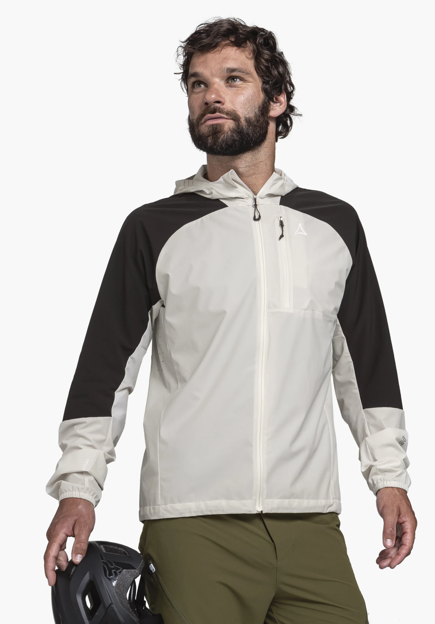 Hybrid Jk Style Mamry MNS. A model stands frontally against a neutral background, presenting the jacket in the colour natur with contrasting black sleeves. The model is holding a bicycle helmet in his hand. The Schöffel logo is clearly visible on the left chest.