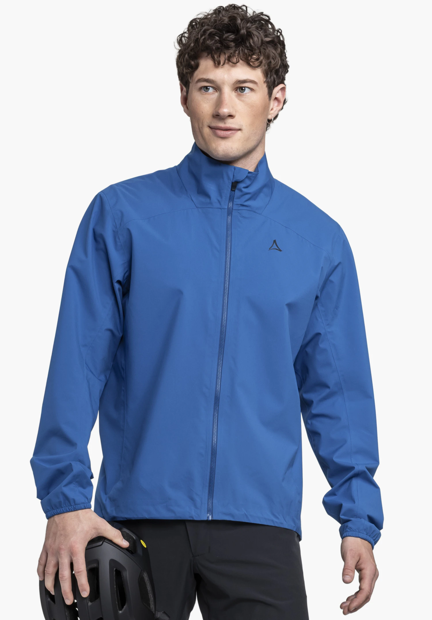 Jacket Style Lurbek MNS getragen von einem Model, das frontal steht und einen Helm in der Hand hält. Die Jacke in blau zeigt das sichtbare Schöffel-Logo auf der linken Brust, fotografiert vor einem neutralen Hintergrund.
