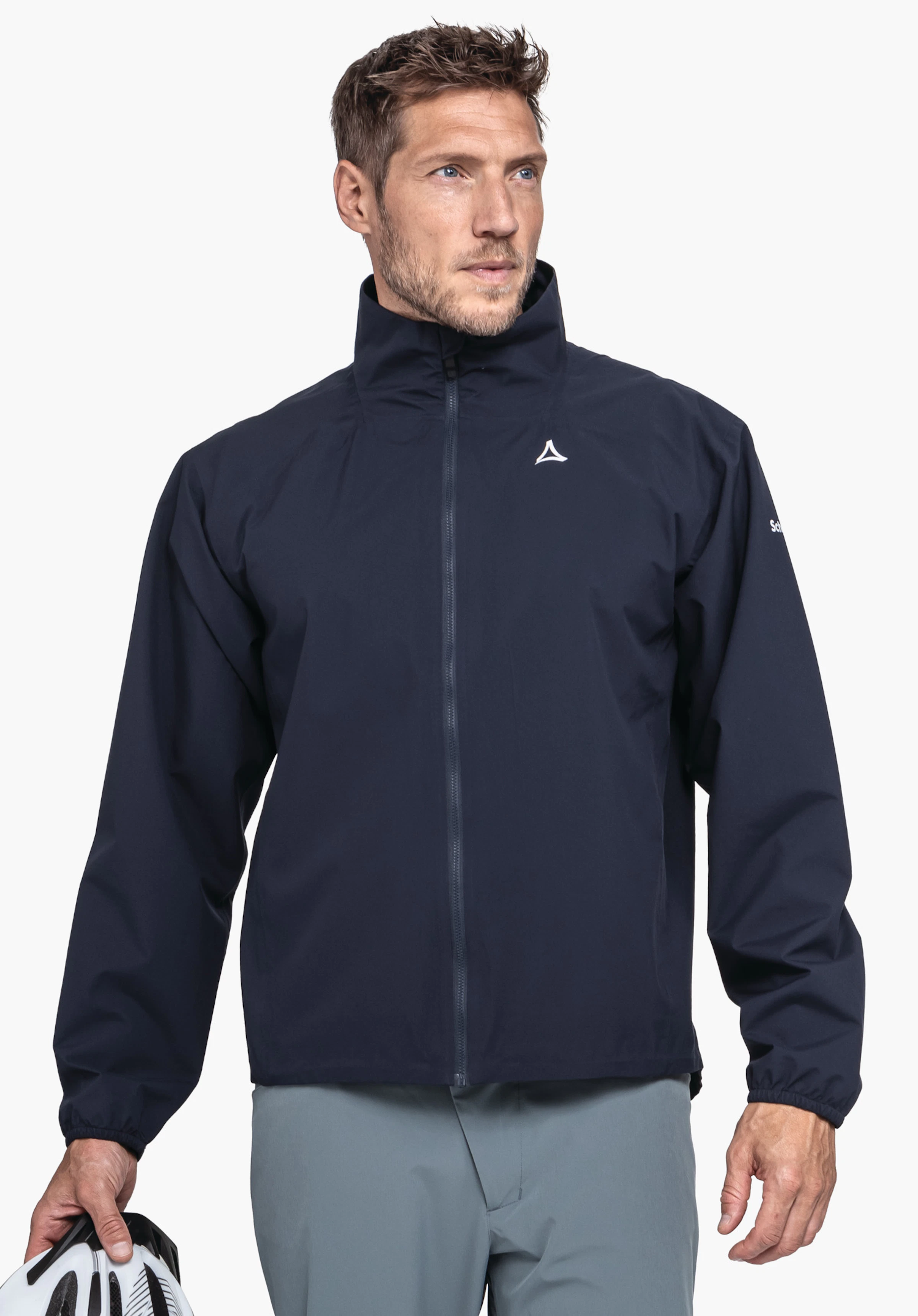 Jacket Style Lurbek MNS Dunkelblau Regenjacke, Mann trägt sie, steht blickend nach rechts, hält weiß-schwarz Fahrradhelm in linker Hand; heller Hintergrund; Schöffel-Logo auf Brust, Schriftzug "Schöffel" auf Ärmel.