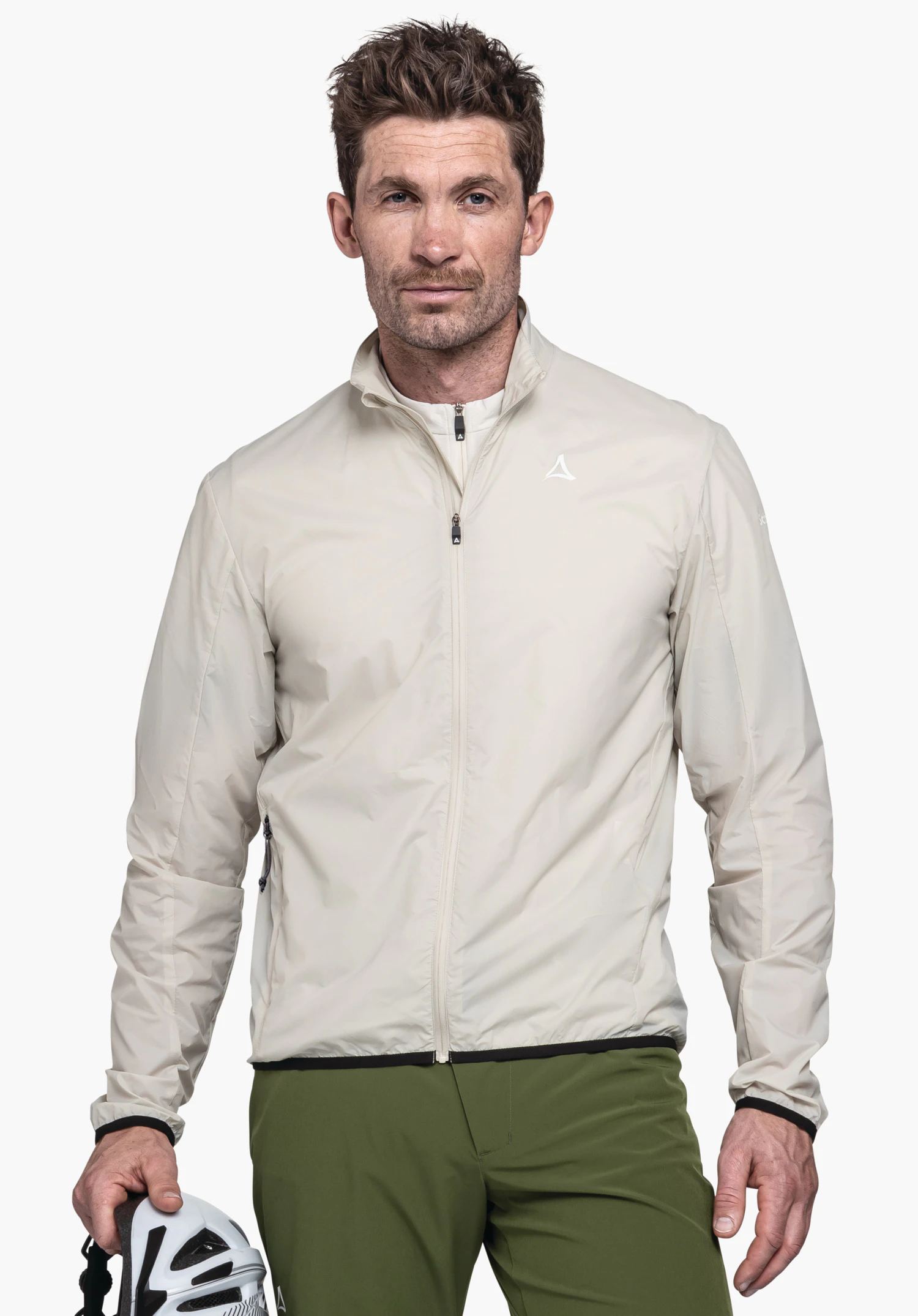 Jacket Style Cannobio MNS in the colour nature. A model stands frontally wearing the zipped-up jacket, with the Schöffel logo visible on the left chest. The model is holding a bicycle helmet in his hand against a neutral background.