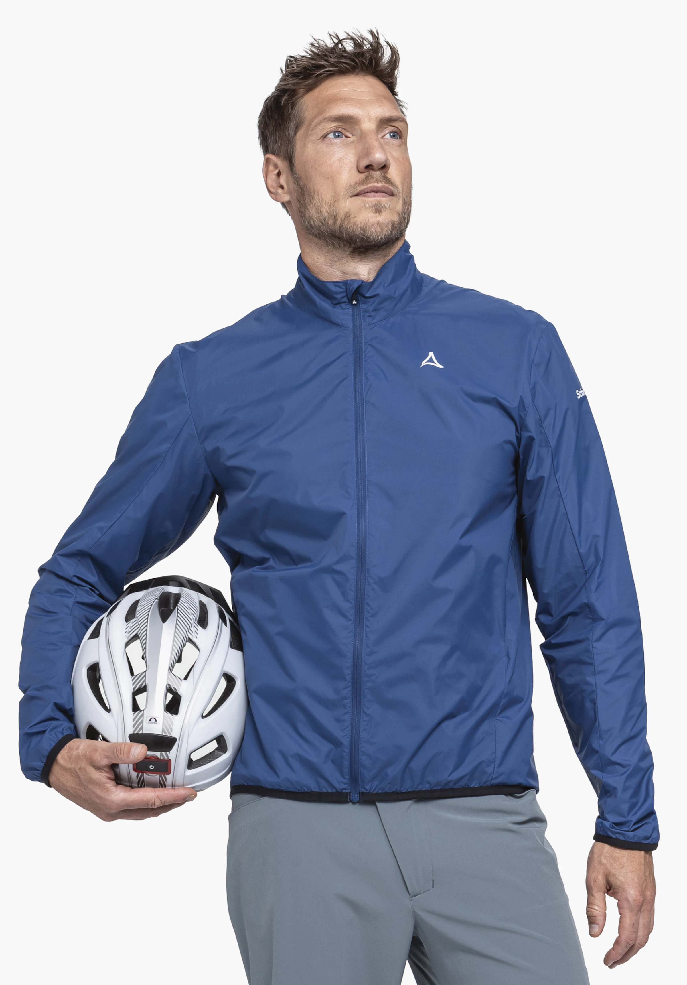 Jacket Style Cannobio MNS donkerblauwe herenjas, gedragen door een man die zijwaarts een witte fietshelm vasthoudt; Schöffel-logo op de borst, opschrift "Schöffel" op de mouw, neutrale witte achtergrond. Tekst: "Schöffel".