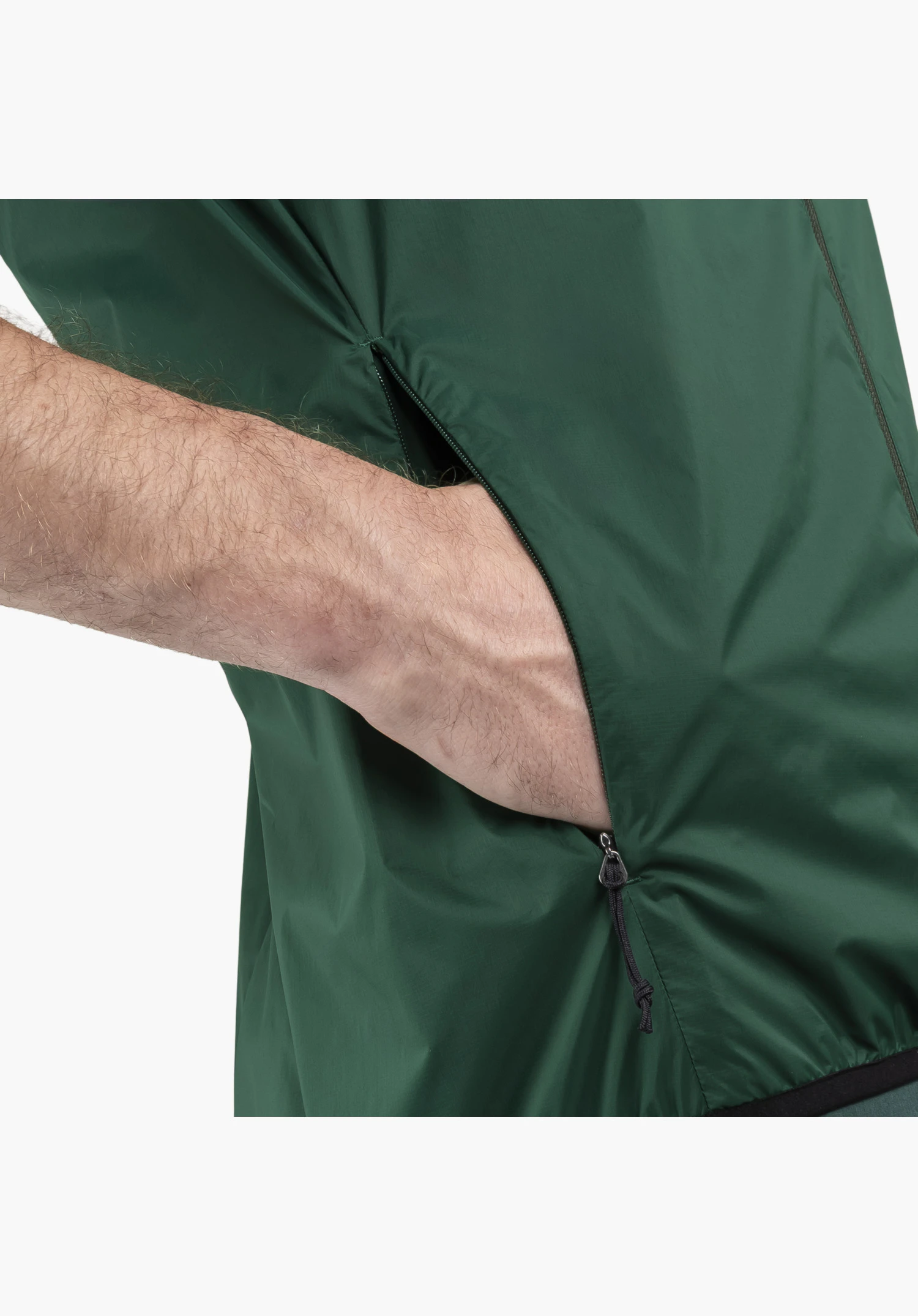 Vest Style Cannobio MNS, hand in the zipped side pocket of the green fabric with a black zip puller, close-up against a white/neutral background.