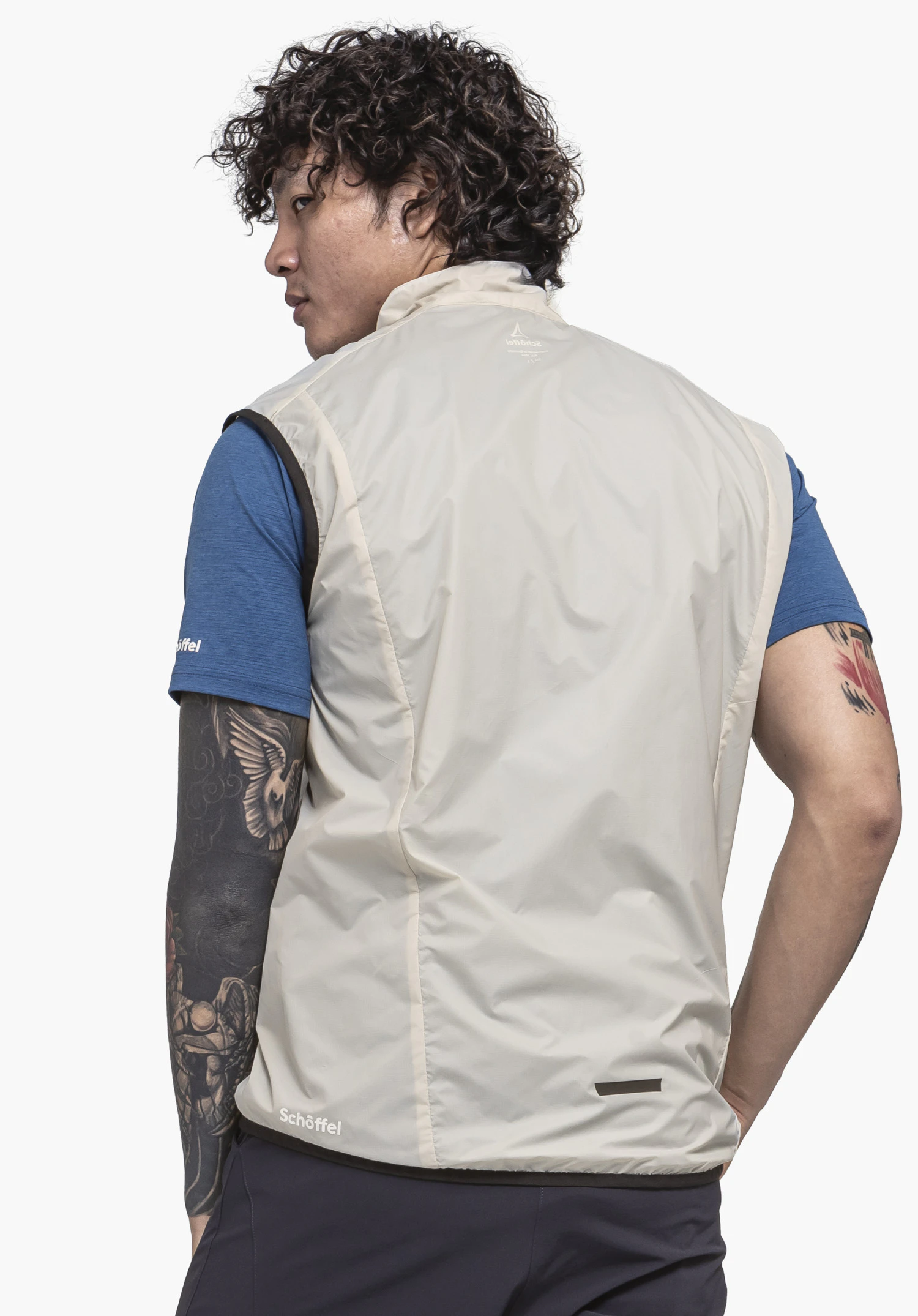 Vest Style Cannobio MNS in der Farbe natur, gezeigt in der Rückenansicht an einem Model vor einem neutralen Hintergrund, mit sichtbarem Schöffel-Logo am unteren Saum.