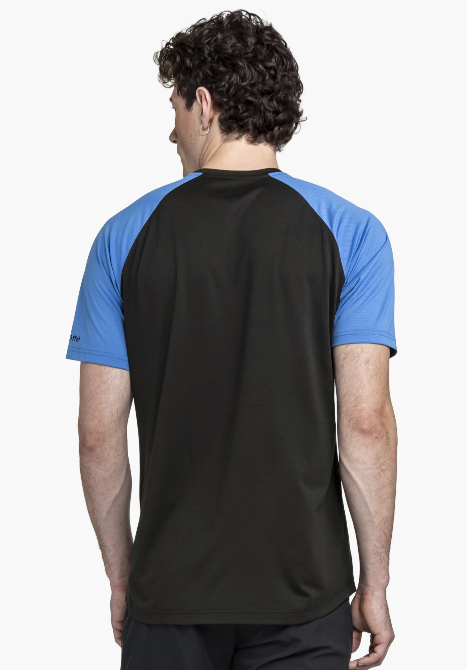 CIRC Shirt Style Wetluga MNS shown from the back against a neutral background. The model wears the shirt in a black colourway with blue sleeves, featuring the Schöffel logo on the sleeve.