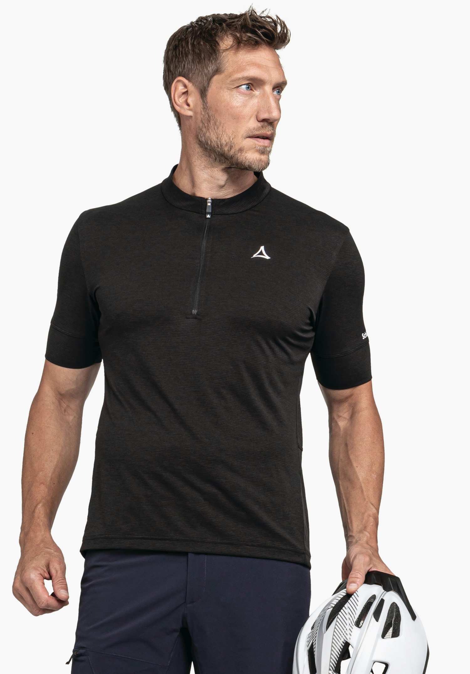 CIRC Shirt Style Pinega MNS in Schwarz vor neutralem Hintergrund. Das Model steht leicht zur Seite gedreht und hält einen Fahrradhelm in der Hand. Das Schöffel-Logo ist dezent auf der Brust zu sehen.