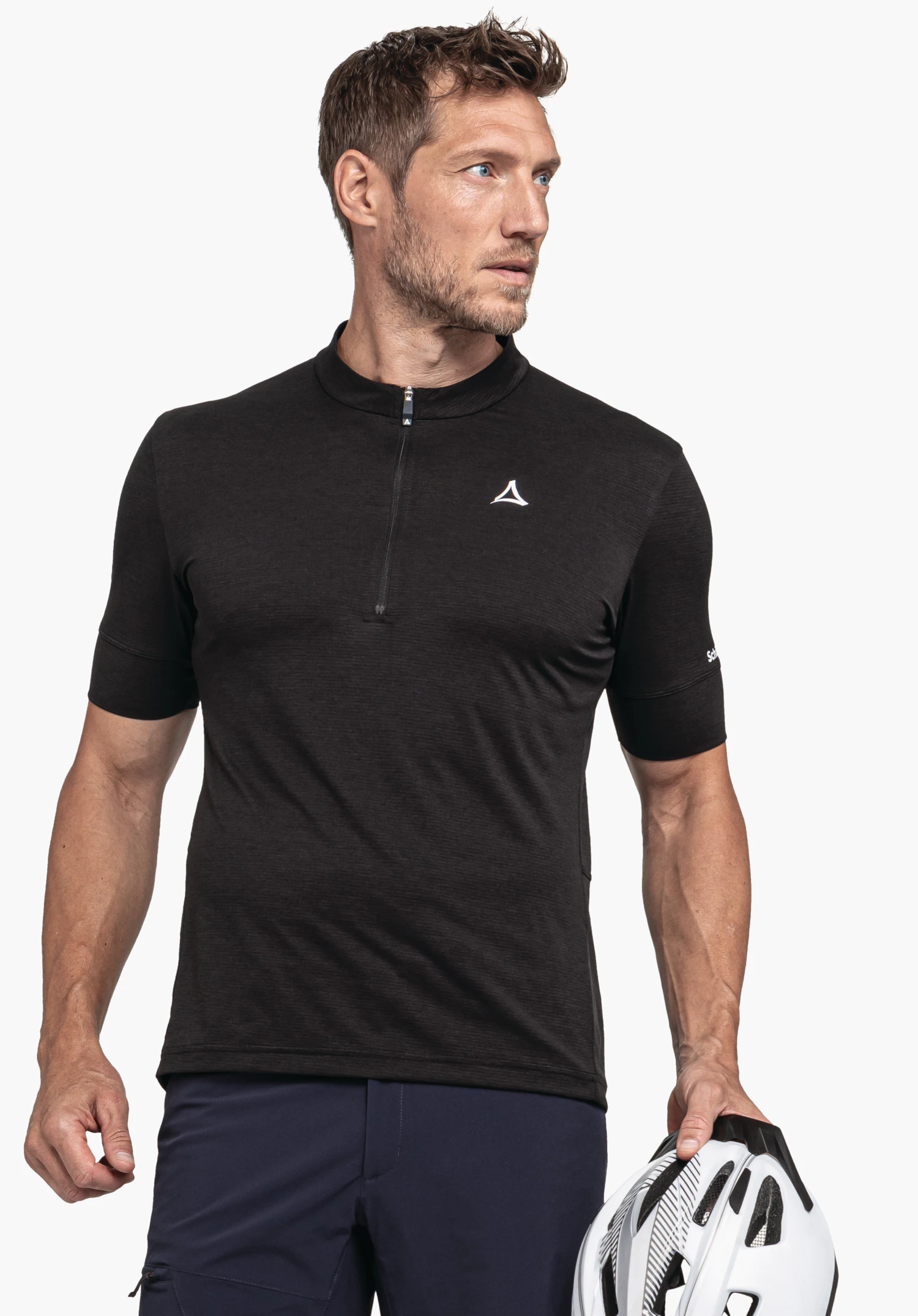 CIRC Shirt Style Pinega MNS in Schwarz vor neutralem Hintergrund. Das Model steht leicht zur Seite gedreht und hält einen Fahrradhelm in der Hand. Das Schöffel-Logo ist dezent auf der Brust zu sehen.