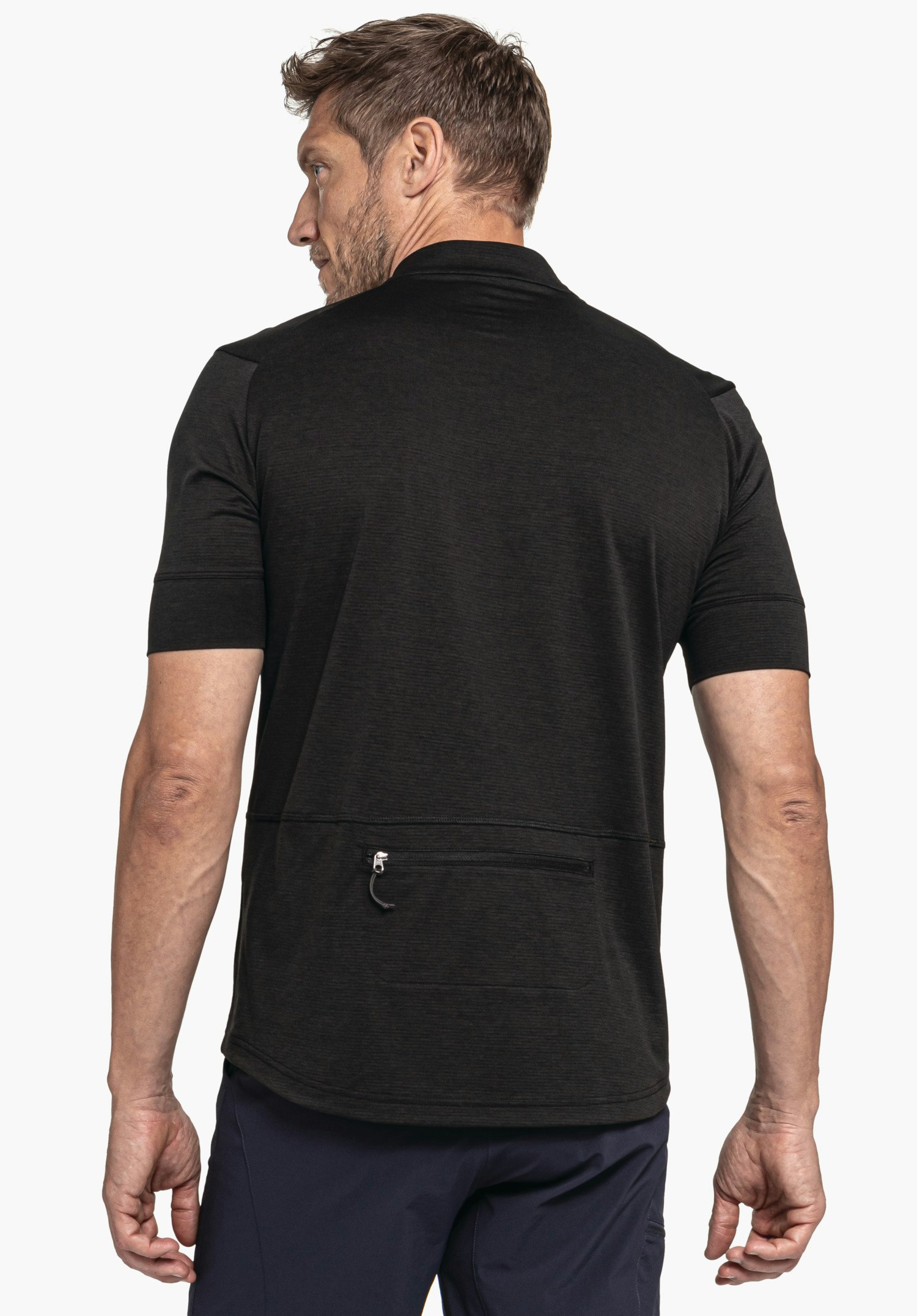CIRC Shirt Style Pinega MNS in Schwarz zeigt sich in der Rückenansicht auf neutralem Hintergrund. Der Fokus liegt auf der Rückseite des Shirts mit der praktischen Reißverschlusstasche, während der Kopf des Models leicht zur Seite gedreht ist.