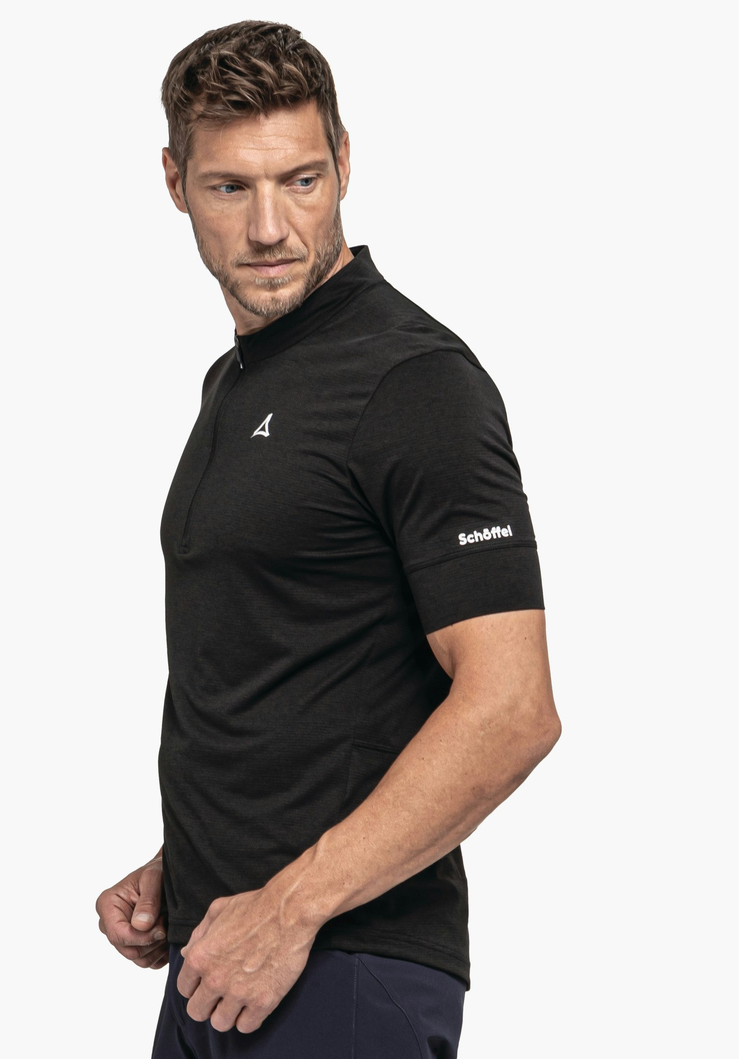 CIRC Shirt Style Pinega MNS zeigt ein Model in einer seitlichen Pose, das das schwarze Shirt vor einem neutralen Hintergrund trägt; das Schöffel-Logo ist auf der Brust und am Ärmel sichtbar.
