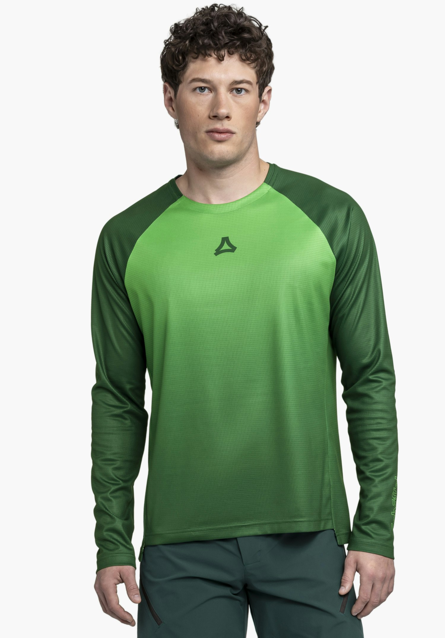 Longsleeve Style Koitere MEN präsentiert sich an einem männlichen Model, das frontal vor einem neutralen Hintergrund steht. Das Shirt in einem dynamischen Grün besticht durch seine Passform und das dezent platzierte Schöffel-Logo im Brustbereich.
